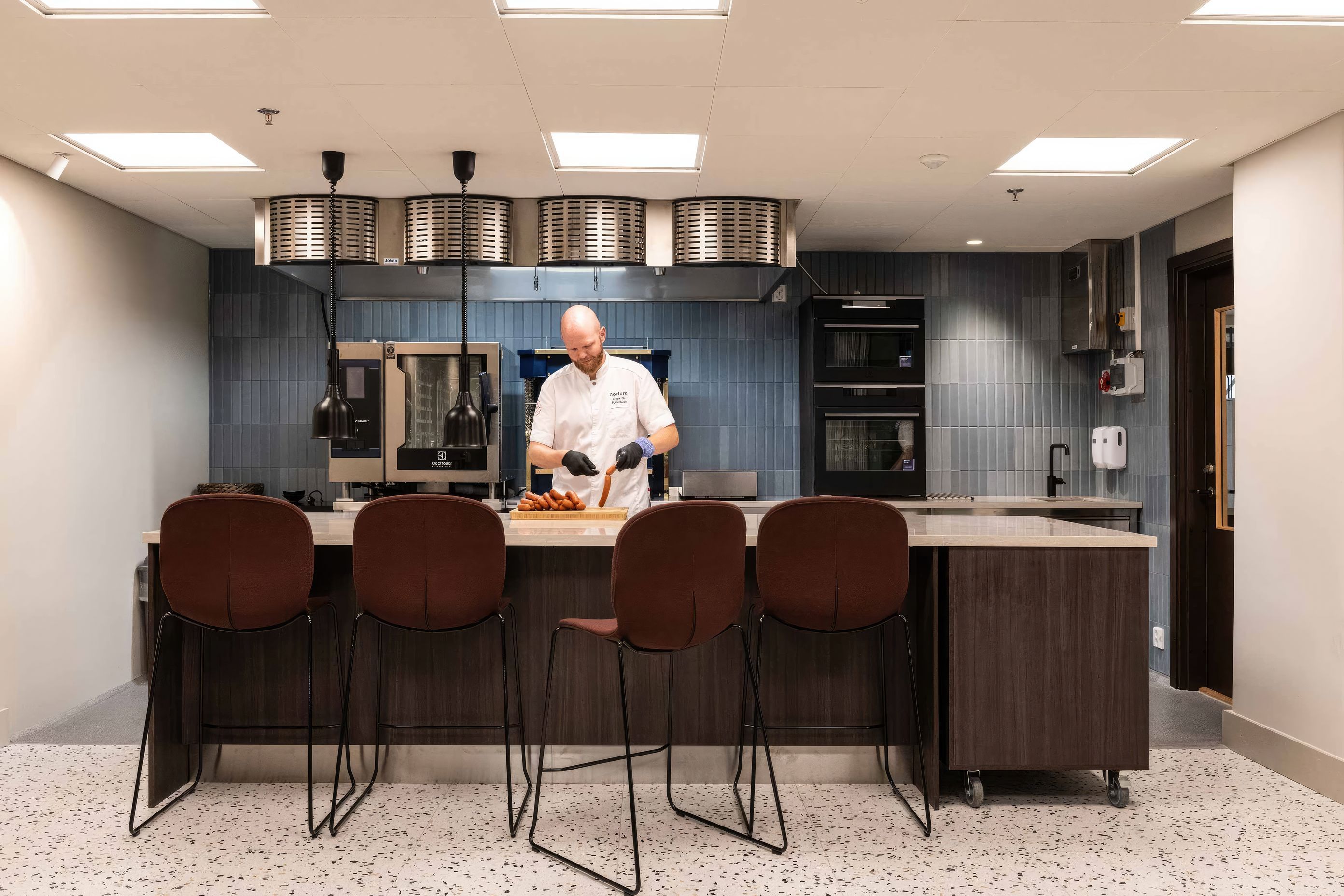 Nortura's show kitchen, previously hidden at the back of the office, was now brought to the heart of the office, signalling its impotance and bringing everyone closer to the food Nortura create.  Featured Flokk design: Profim Noor Up  in Sirdal (SRD630) fabric by Gudbrandsdalens Uldvarefabrik &amp; Flokk