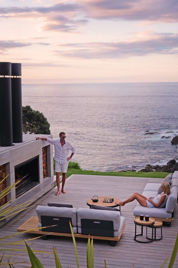 Topher and Bridget lounging in front of their outdoor fireplace at the far end of the home.