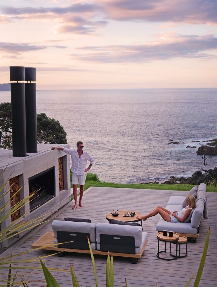 Topher and Bridget lounging in front of their outdoor fireplace at the far end of the home.