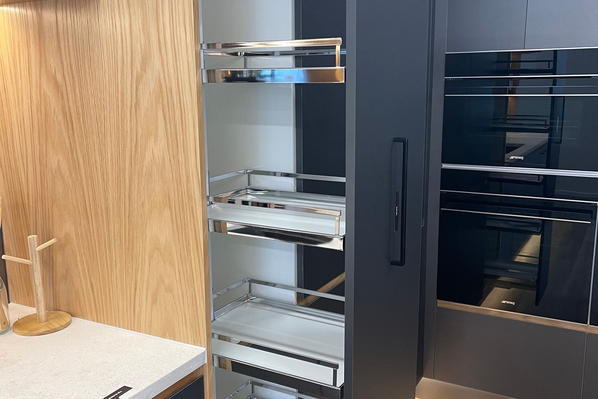 Pull out pantry with in-built shelves makes it easy for you to clearly see all the stored items and retrieve them. – This pantry can be seen in our matte black kitchen display in our Kitchen showroom in Auckland.