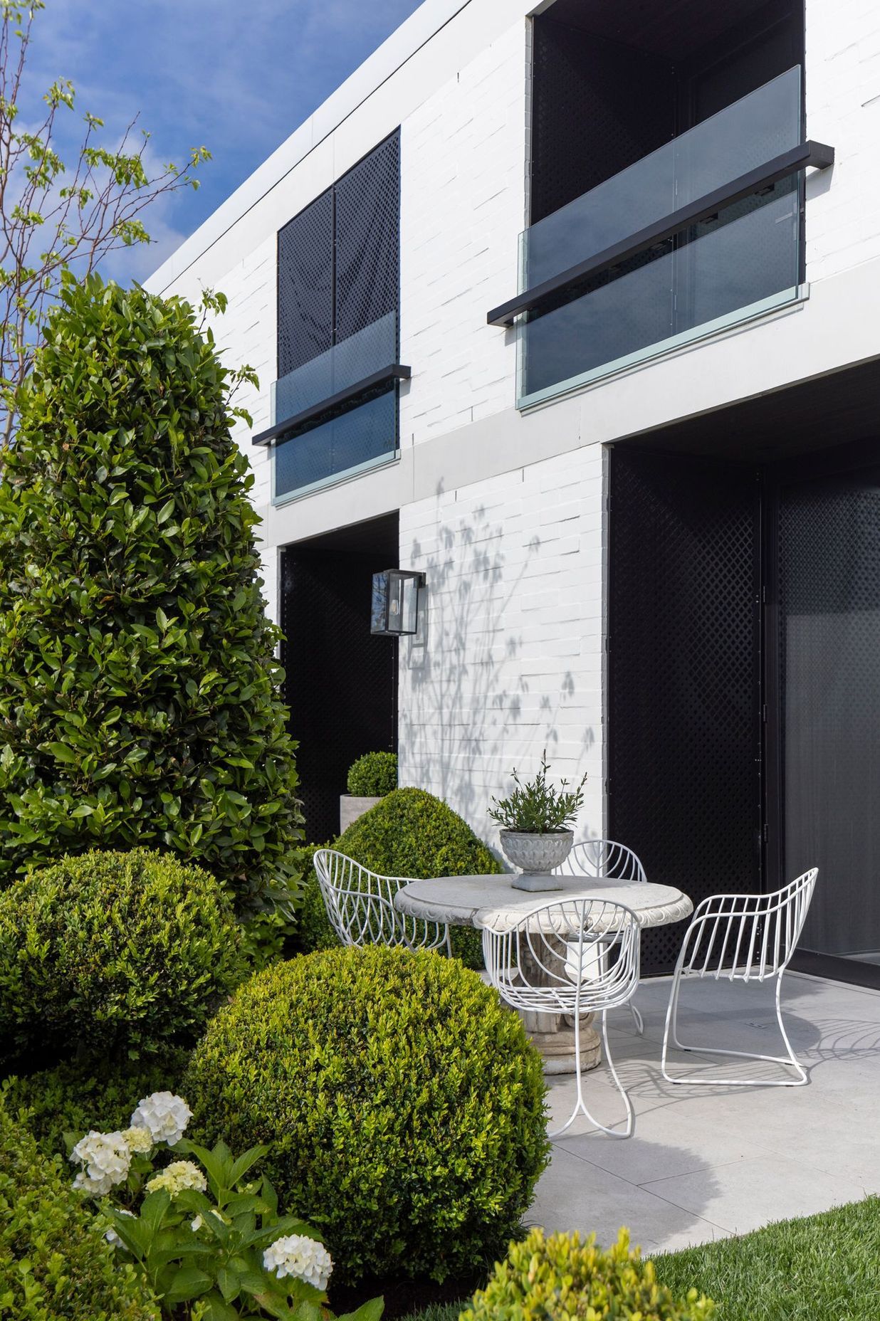 An intimate courtyard is hidden from the road by an abundance of greenery, yet still offers sweeping views of Remuera.