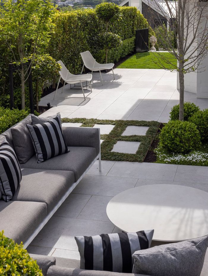 Two courtyards are separated by pavers bordered by soft ground cover.