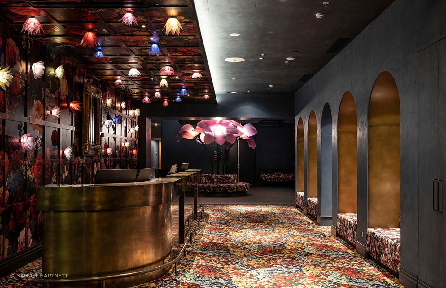 “There were already arches in all the doorways in the building, so we replicated them throughout to tie that through,” says Material Creative’s Toni Brandso. The flower lights and the oversize sculpture were created by Angus Muir Design.
