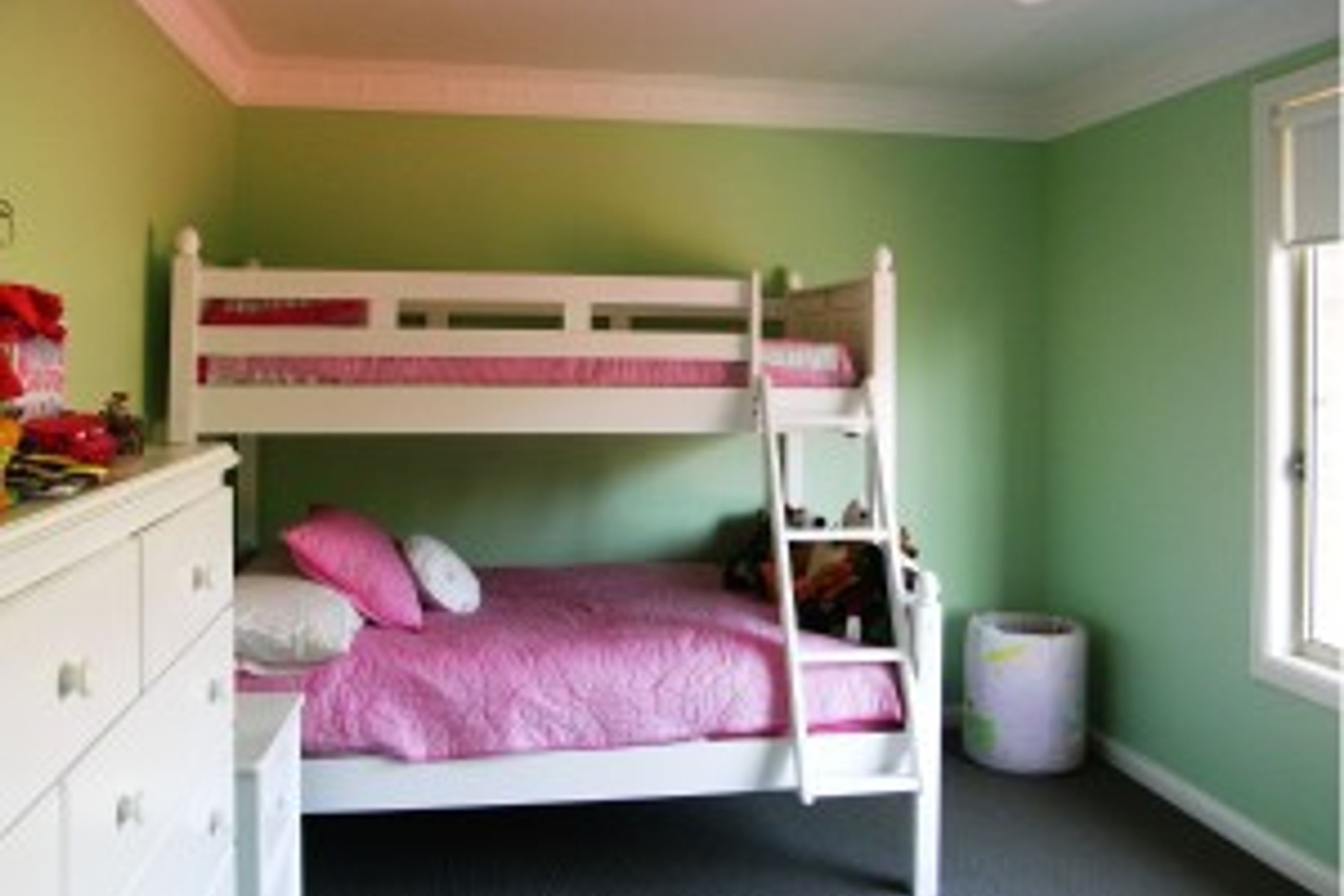 Pink bed linen contrasts but compliments the green walls