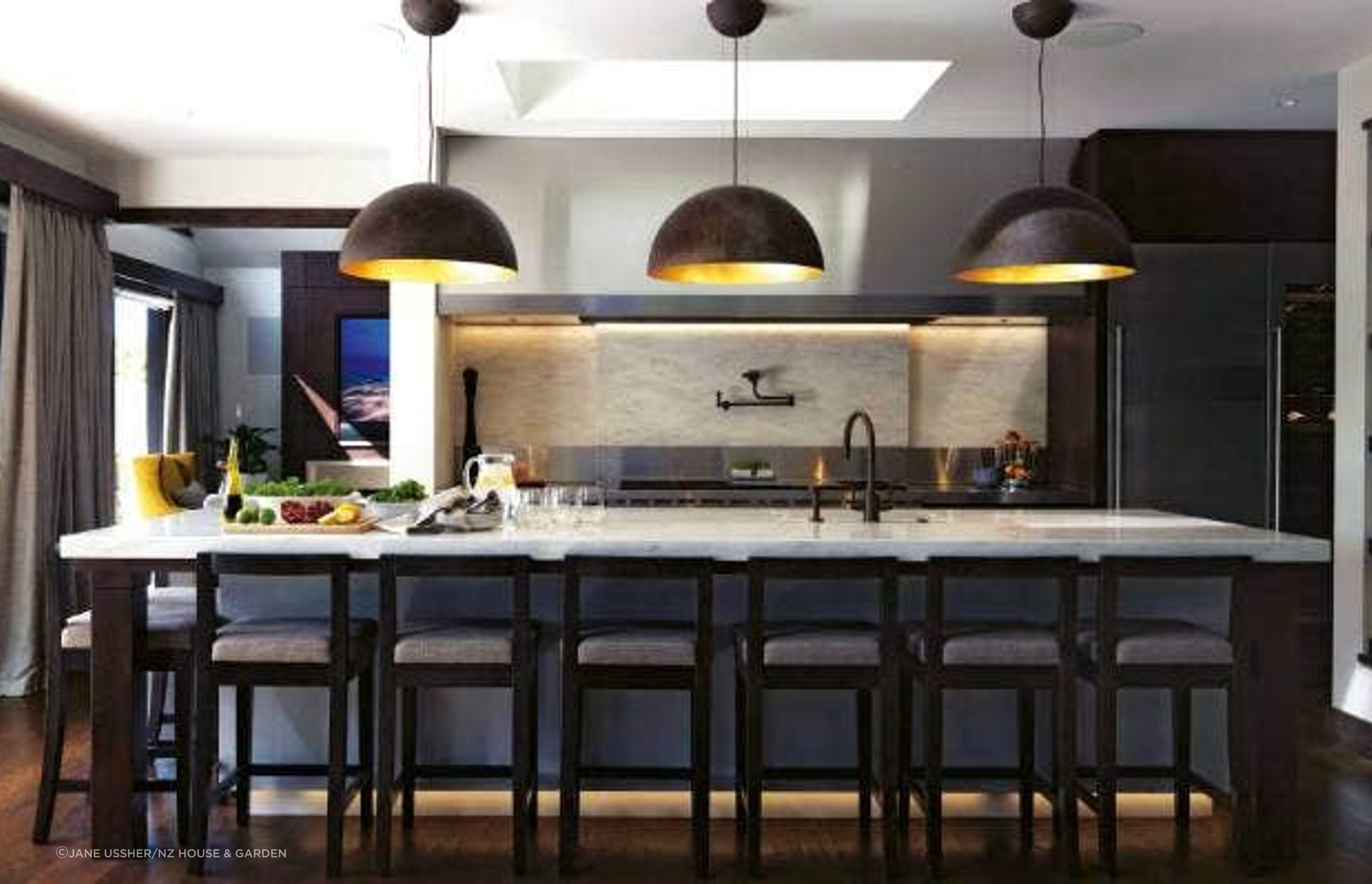 Entertaining was at the heart of the McNalls' plans for rebuilding their West Harbour home, so behind the main kitchen is a scullery with a commercial oven and dishwasher; the Corian benchtop is a soft contrast to the stainless steel and the light shades are from Lighthouse; the bar stools were custom-made by Modern Chair in Mt Roskill.