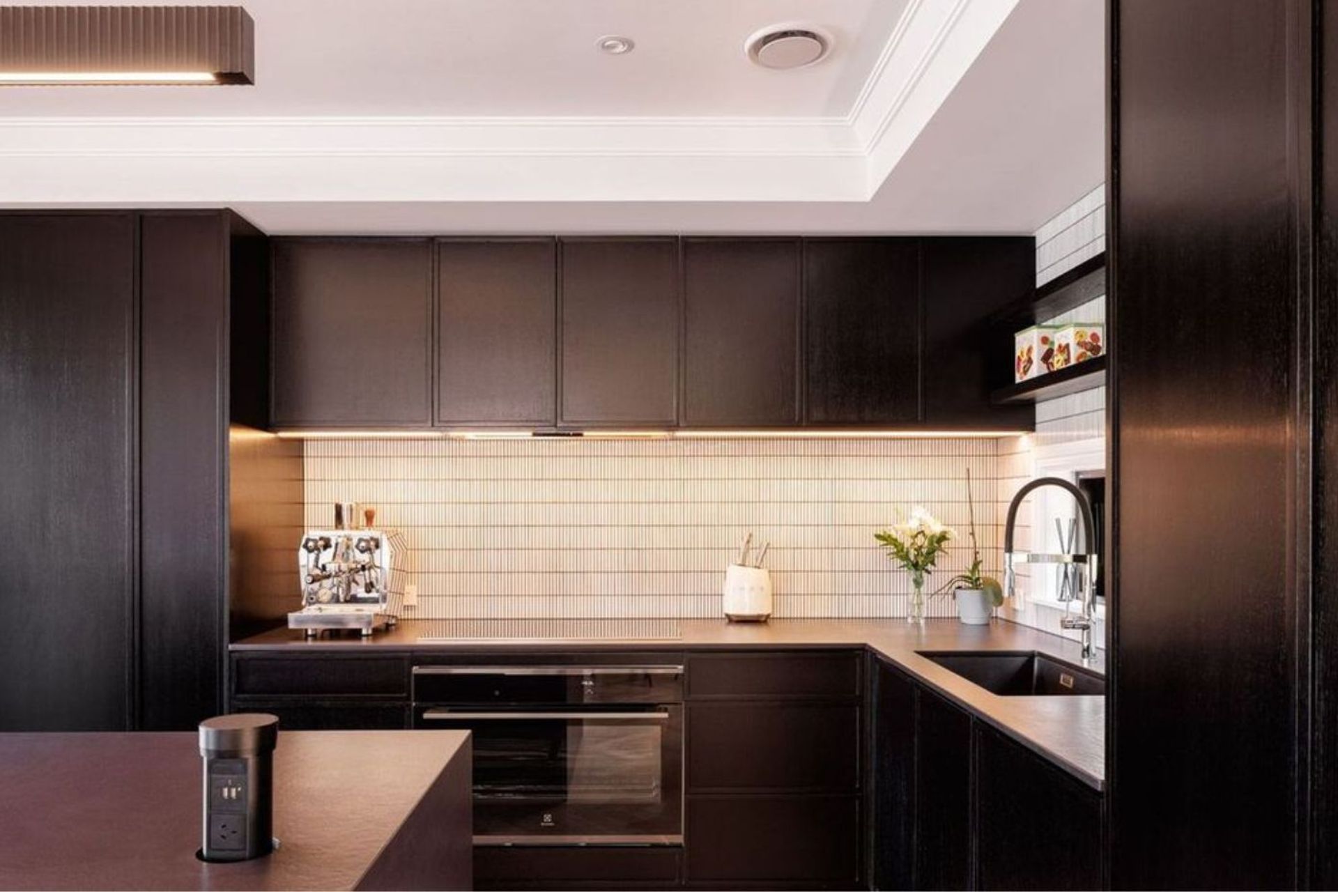 The kitchen, also known as the heart of the home, is designed with dark stained wooden cabinets, sublty lightened with white tiling to add texture and contrast