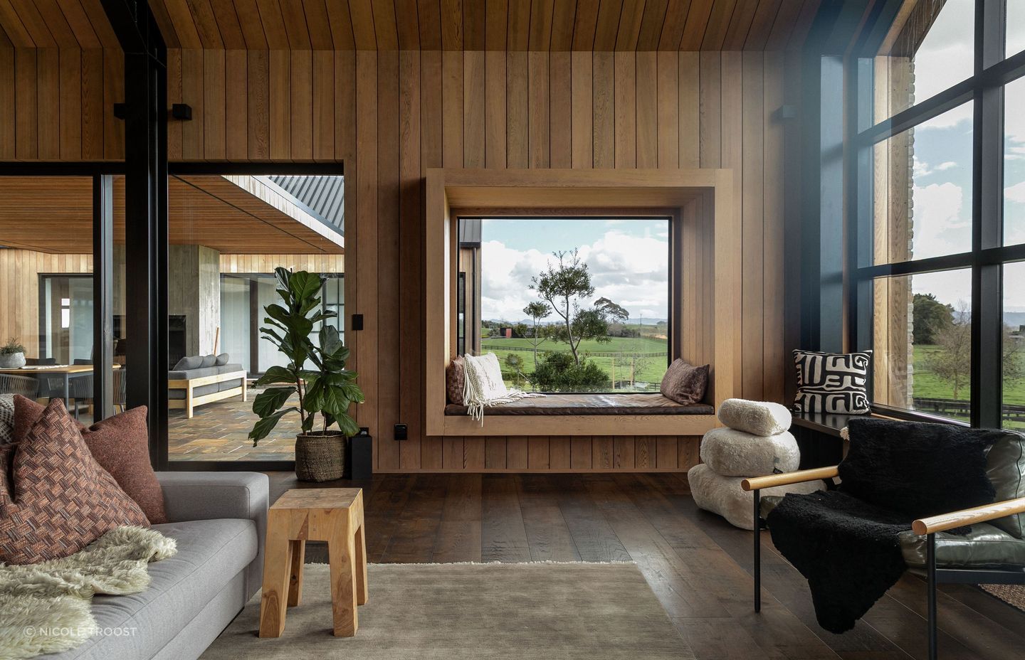 The living space sandwiches an outdoor courtyard between it and the guest wing; a picture window with built-in seating is the perfect spot for reading.