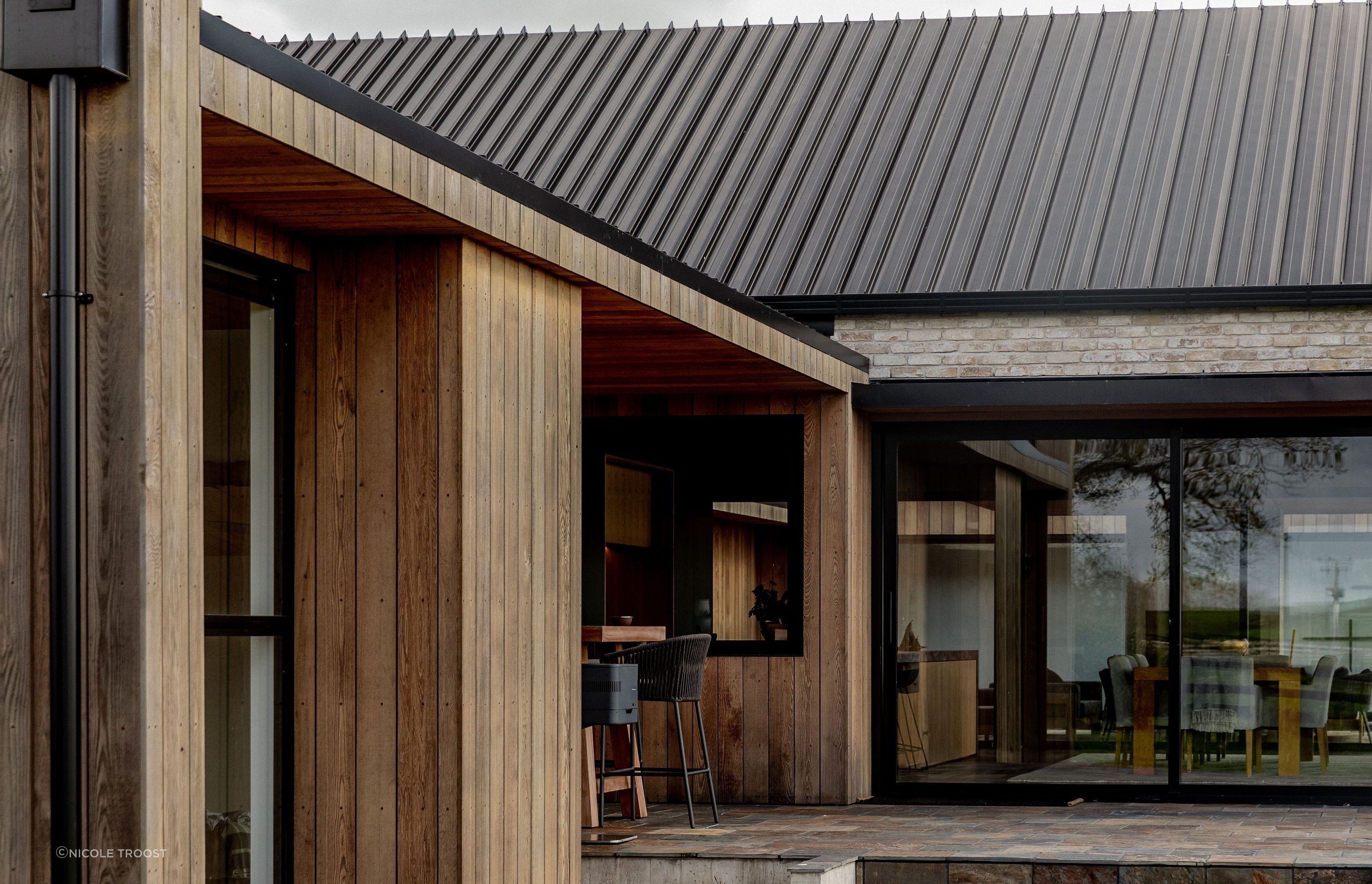 On either side of the living room gable building are sheltered stone courtyards, flanked with brick and cedar-clad walls.