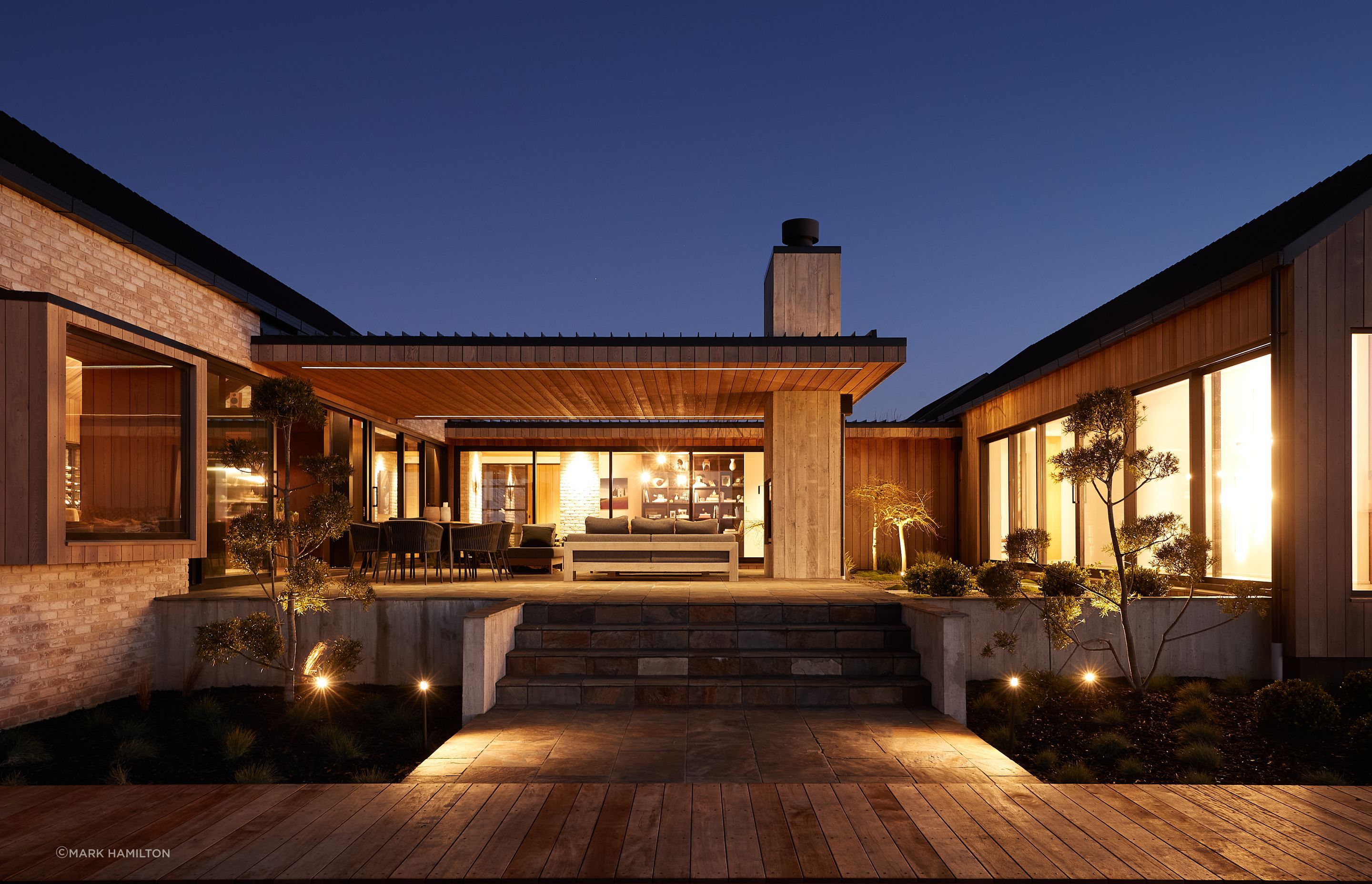 Photo credit: Mark Hamilton. The outdoor internal courtyard with built-in outdoor fireplace features slate paving and Zen garden-like plantings.