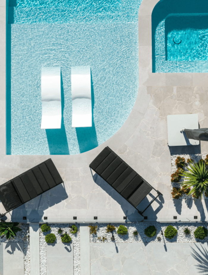 Phillip Bay Coastal Sanctuary by Design Native. Luna Chiaro Limestone in Alfresco finish anchors the pool and entertaining areas with clean lines and a refined neutral palette. Custom formats including 800×400mm and 1000×1000mm pavers showcase 2025's refined residential design.