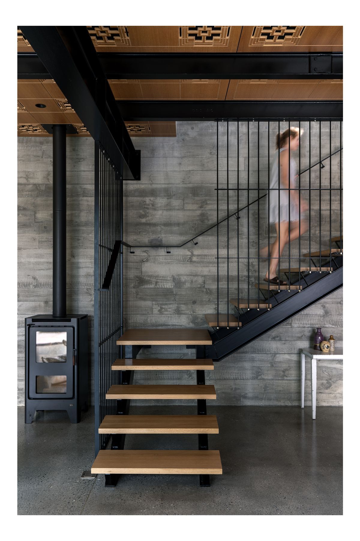 “That fireplace basically heats all of this area. We do have some ducted heat pumps. But to be honest, in the summer, we leave all the windows open and don't need it and in the winter, we light the fireplace at five o'clock and it heats the house all evening.”  Clive has collected some second-hand furniture. “I like something that's got a little life to it. It's got a history rather than something brand new.” The Michael Draper table under the stairs was bought when he closed down his factory. “So I've just cleaned all the grease off it, and we've had it for years. I keep putting it into whichever house we live in.”