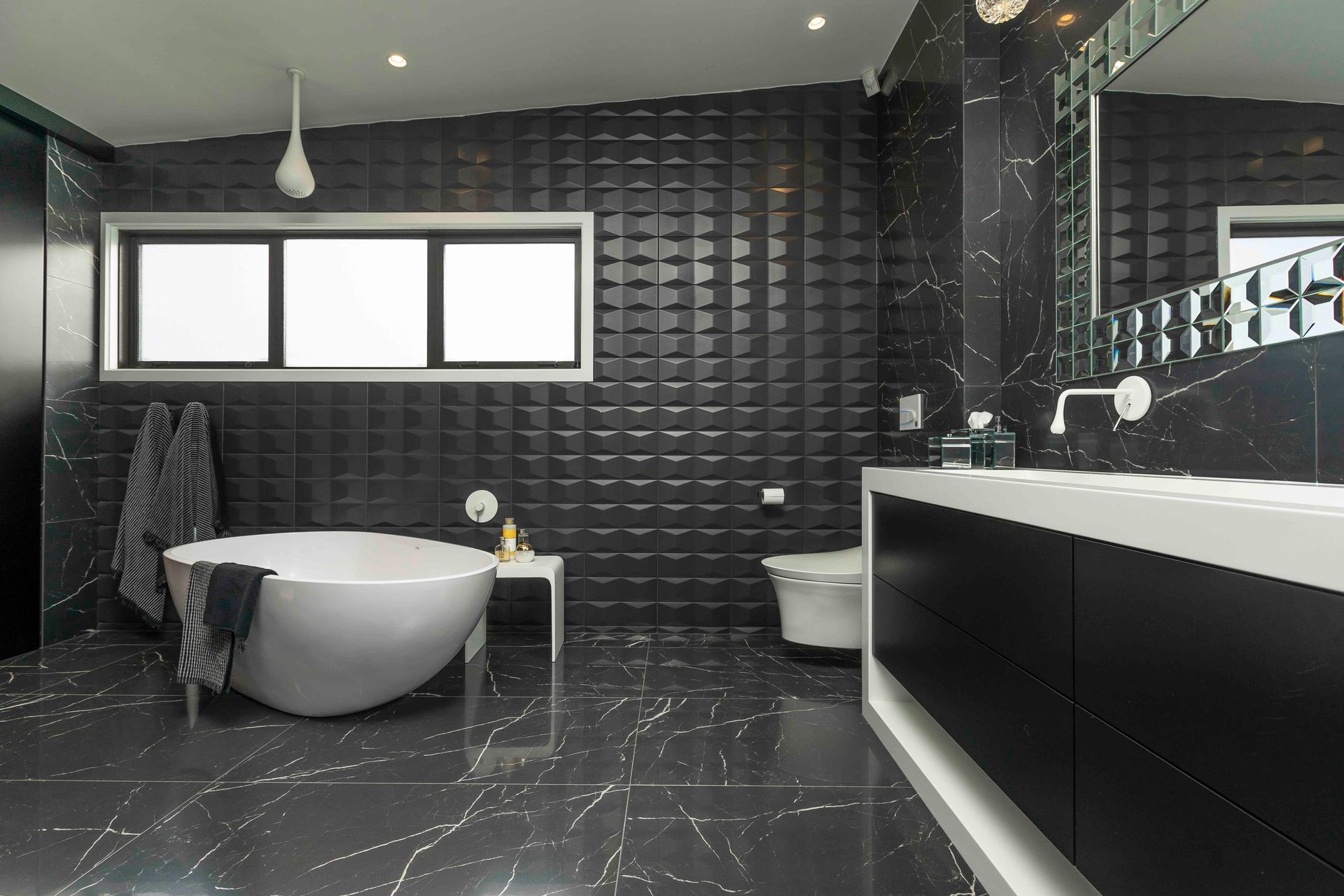 This master ensuite in Wiri personifies texture and depth with its use of textured bathtub surround tiles.