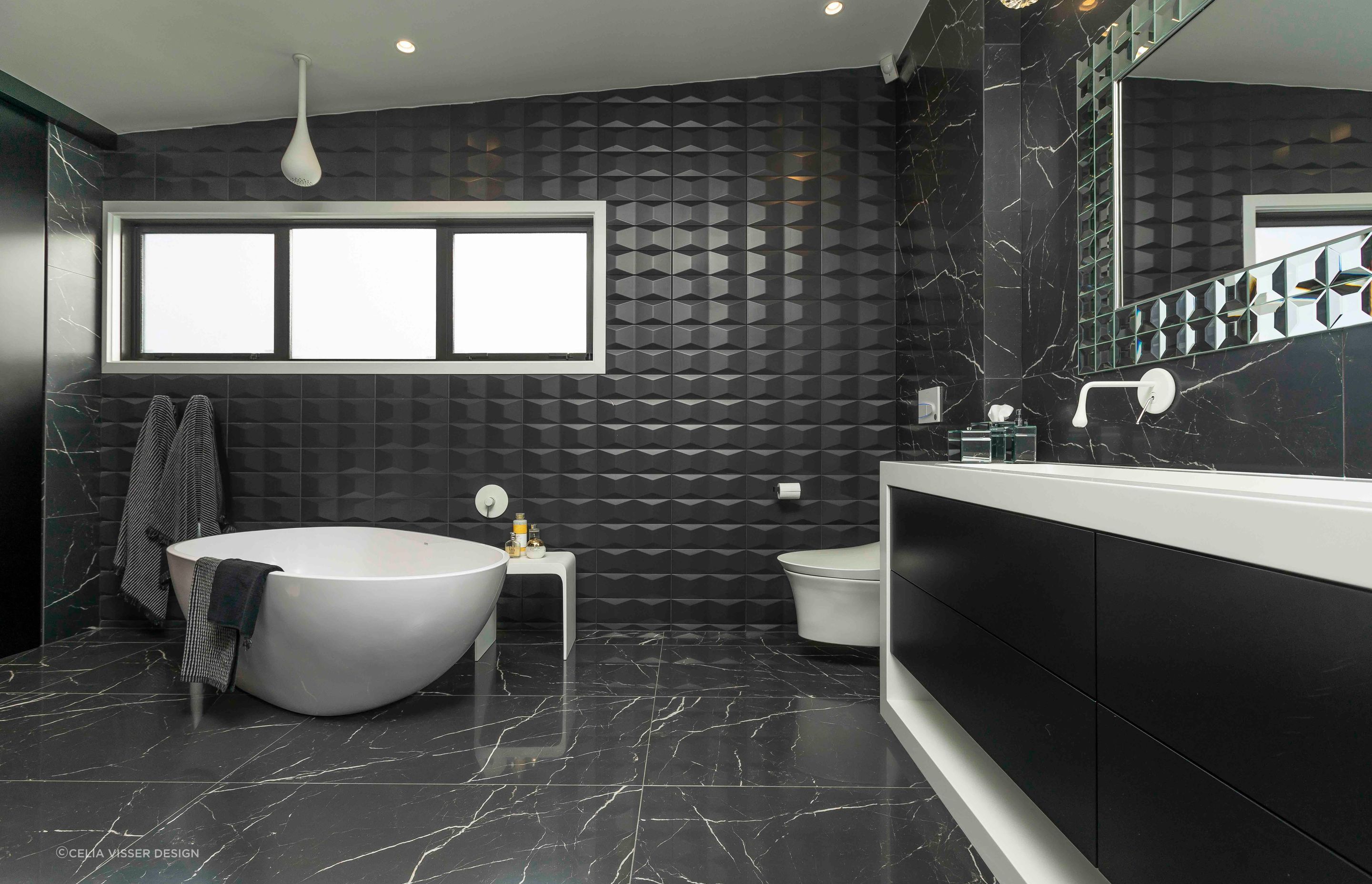 This master ensuite in Wiri personifies texture and depth with its use of textured bathtub surround tiles.