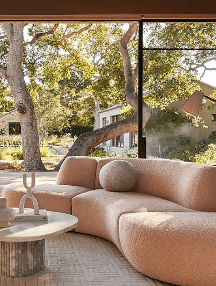 Image Credit:  Anthropologie | Curved Sofa in clay tones + biophilic design