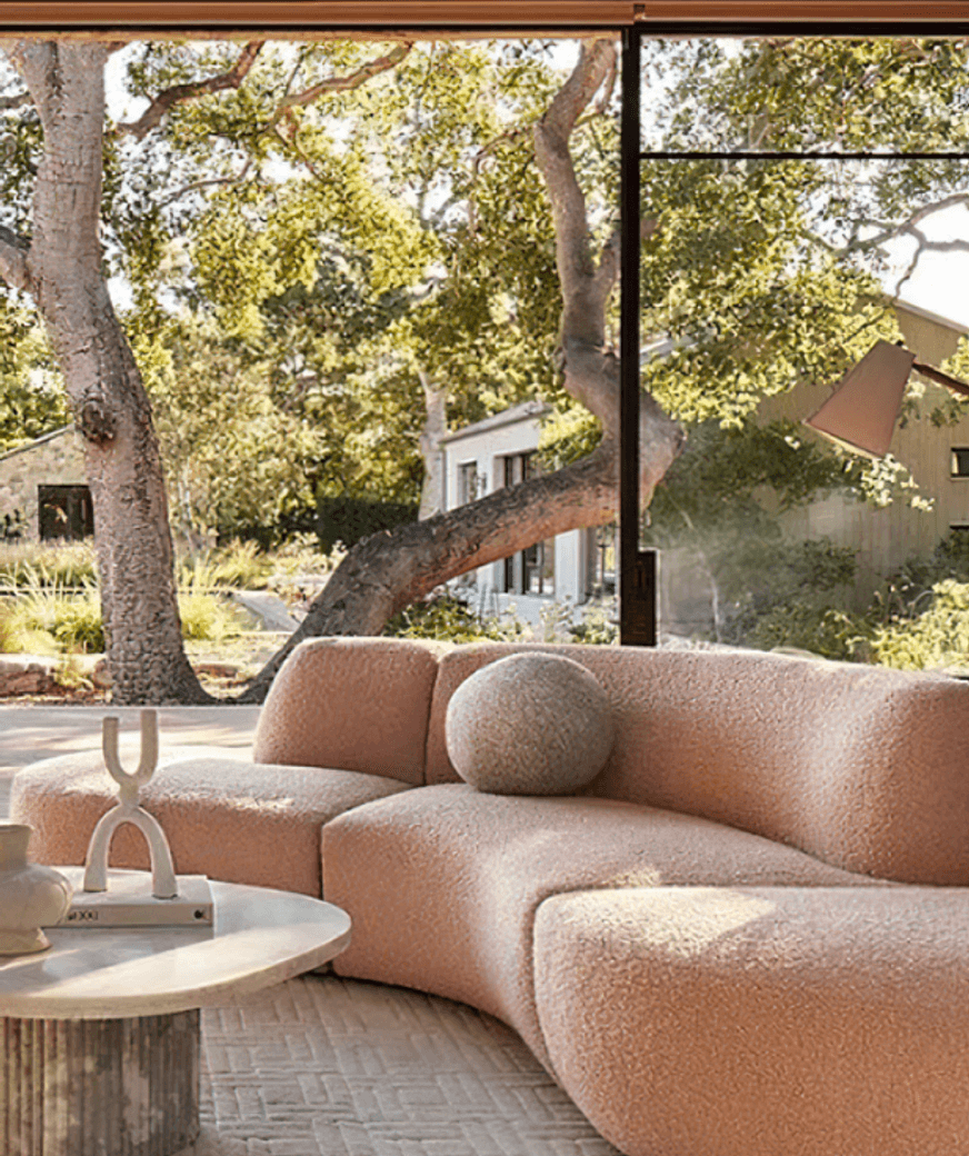 Image Credit:  Anthropologie | Curved Sofa in clay tones + biophilic design