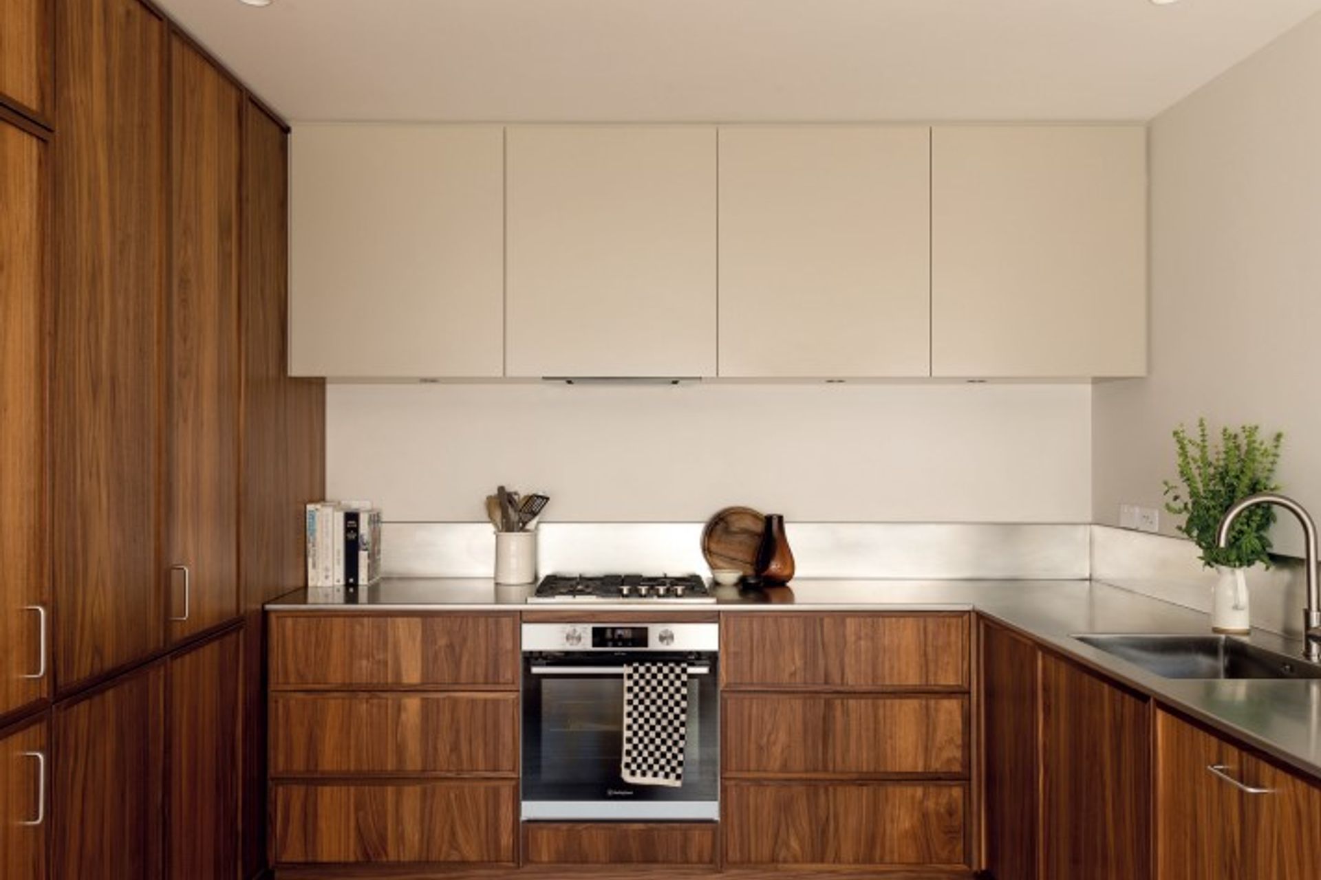KITCHEN Floor-to-ceiling walnut-veneer cabinetry replaced a window in this generous but well-used space. “I always wanted stainless steel,” says Bailey about the utilitarian benchtop and splashback. “We were set on a minimal look and didn’t want a join in the benchtop, so that was a challenge when it came to bringing in the L-shaped piece. Seven guys attempted to place it, but ended up having to cut some of the wall to get it in without disturbing the cabinetry!” Bailey kept the handles here to a minimum as well, using D Pulls by Häfele only where strictly necessary. The appliances are by Fisher and Paykel and Westinghouse, and the Elysian mixer is from ABI Interiors.