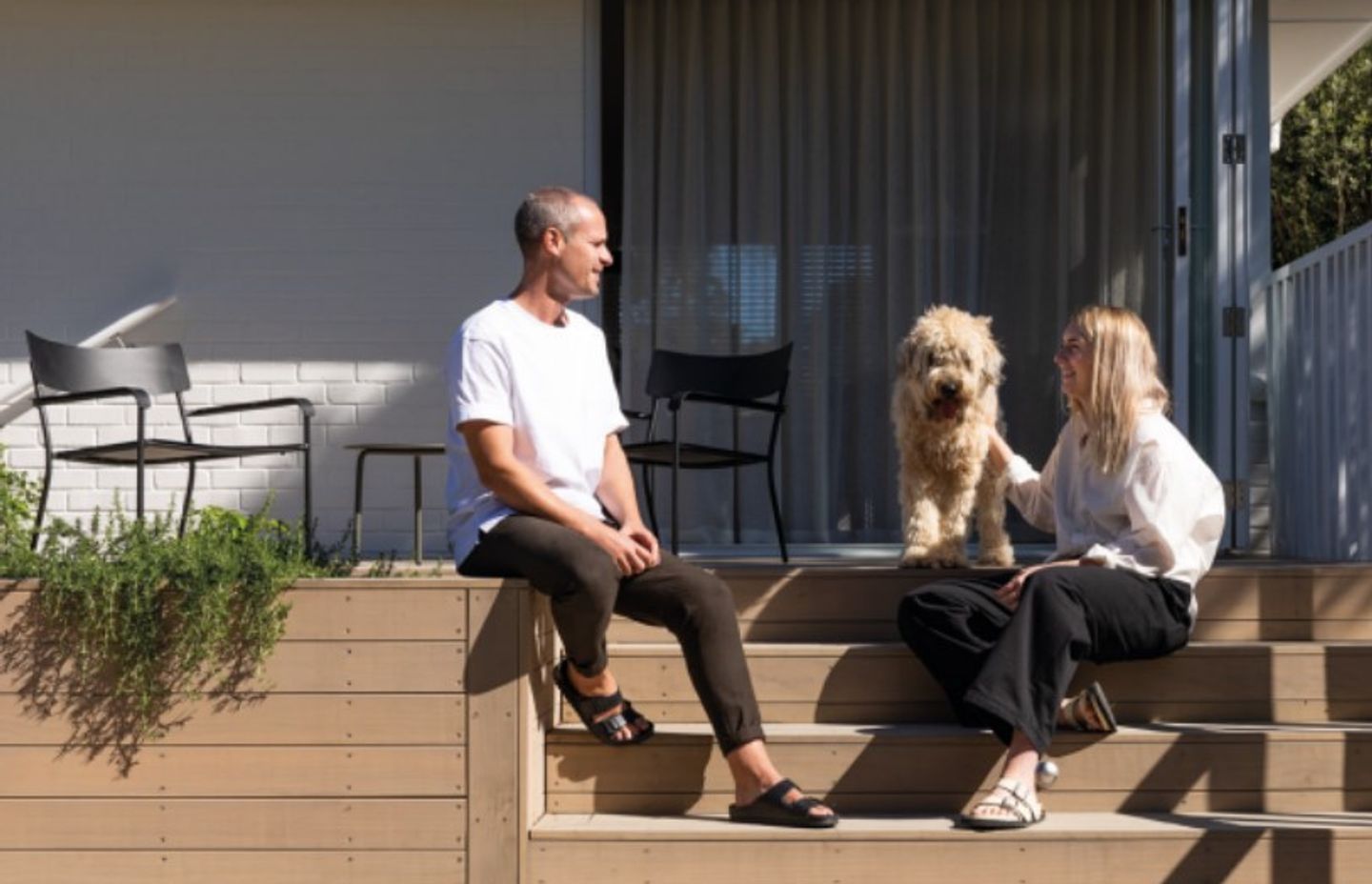 Ali, Bailey and Gruff the dog on their back deck designed by Jared Lockhart, with August chairs and an August side table by Serax from Simon James behind them. Bailey says they really enjoy living in Titirangi. “We love taking Gruff to Piha Beach, and being far enough from the city that it’s quiet, but close enough that I can whip in and meet a friend for a wine or a pilates class. It’s the perfect balance.”