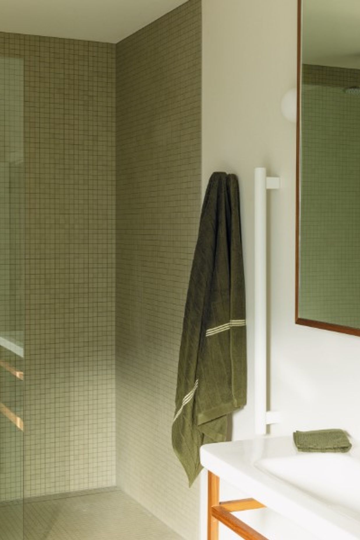 BATHROOM Here, a leggy DuraStyle vanity by Durafit is teamed with Milani tapware from ABI Interiors. The ceramic wall and floor tiles from Artedomus have a matte finish that Bailey sought to sync with the look of the Oasis freestanding bath by Concrete Nation, and the walls are in Porter’s Paints Cashmere to match the other main rooms in the house. On the vanity and Grab 90 rails by Avenir from Plumbline are organic cotton towels by Bailey’s own luxury brand, Baina. Pictured right, a large, frosted-glass window opens like a door to provide maximum ventilation in this space. “In the morning, the sun streams in through it — it’s beautiful,” says Bailey.