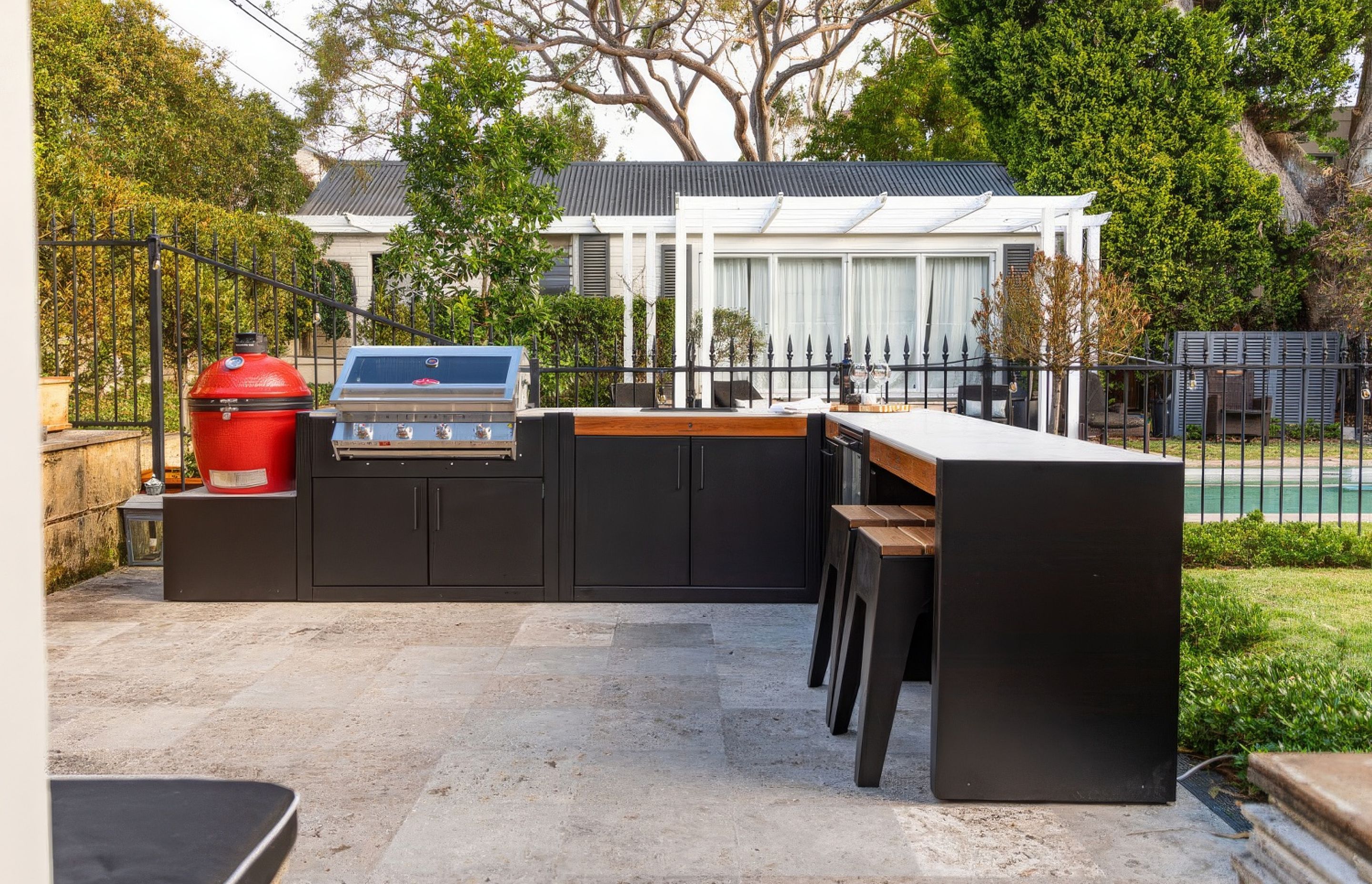 Backyard kitchen with a Kamado smoker, BBQ, sink and bar