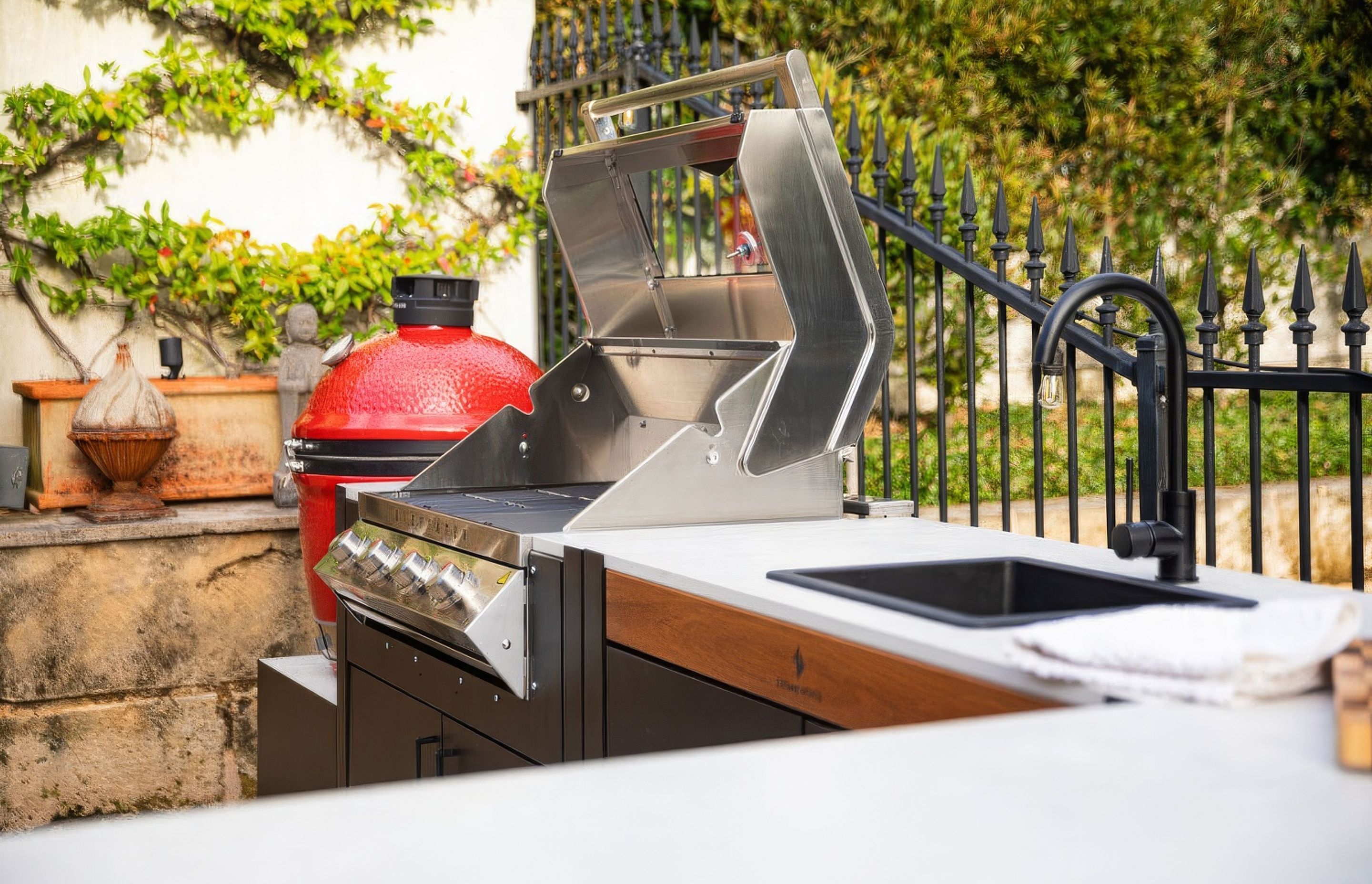 Backyard kitchen with a Kamado smoker, BBQ, sink and bar