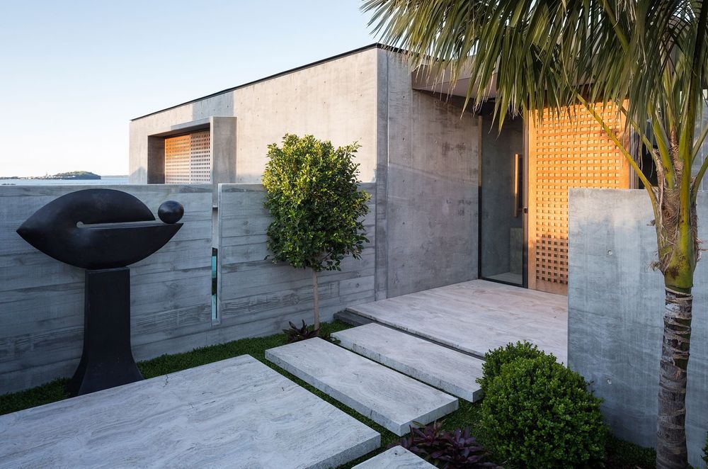 Contrasting textures between the precast concrete cladding and the timber door add depth and dimension to this immaculate home in Hobson Bay
