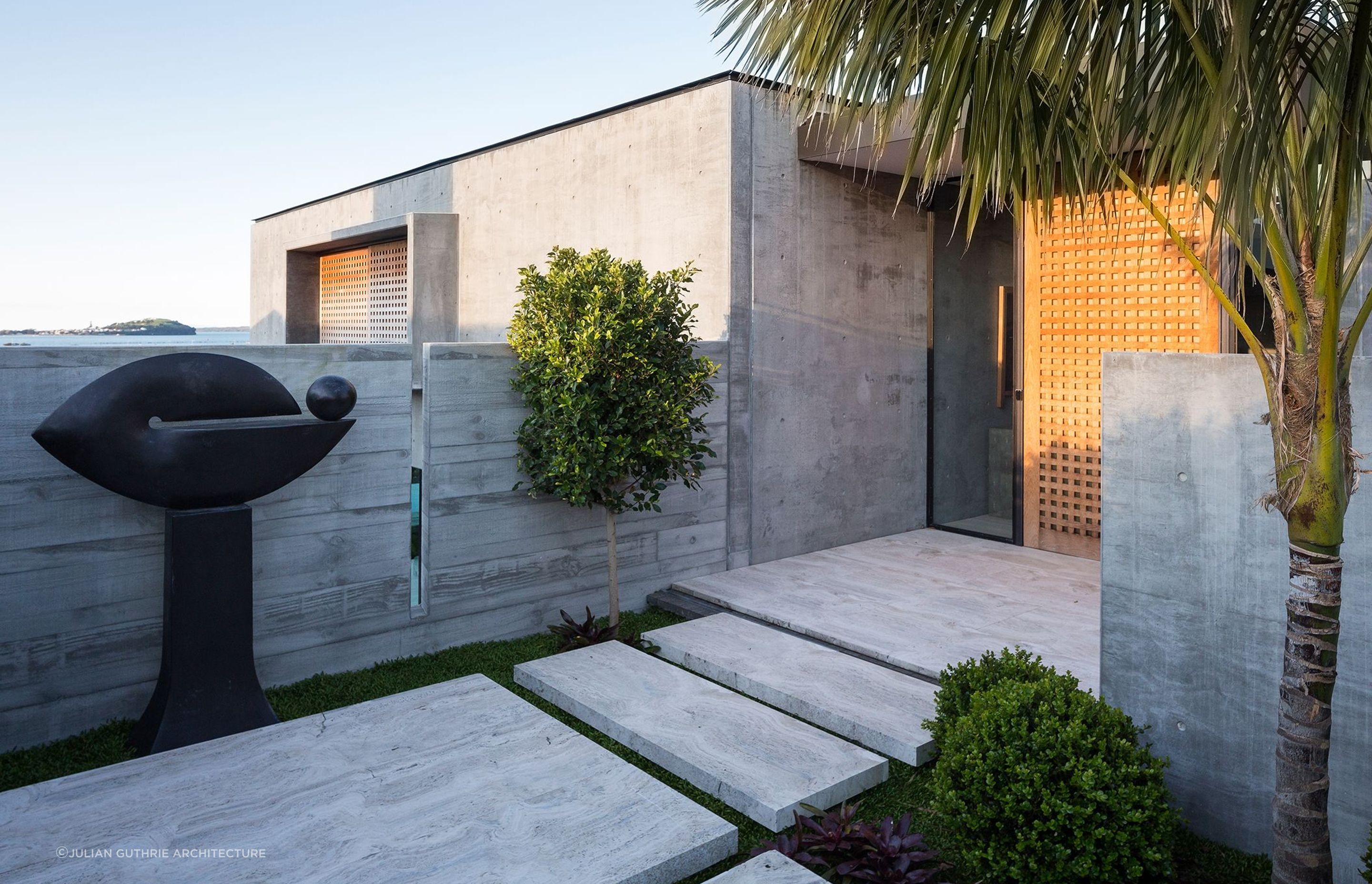 Contrasting textures between the precast concrete cladding and the timber door add depth and dimension to this immaculate home in Hobson Bay