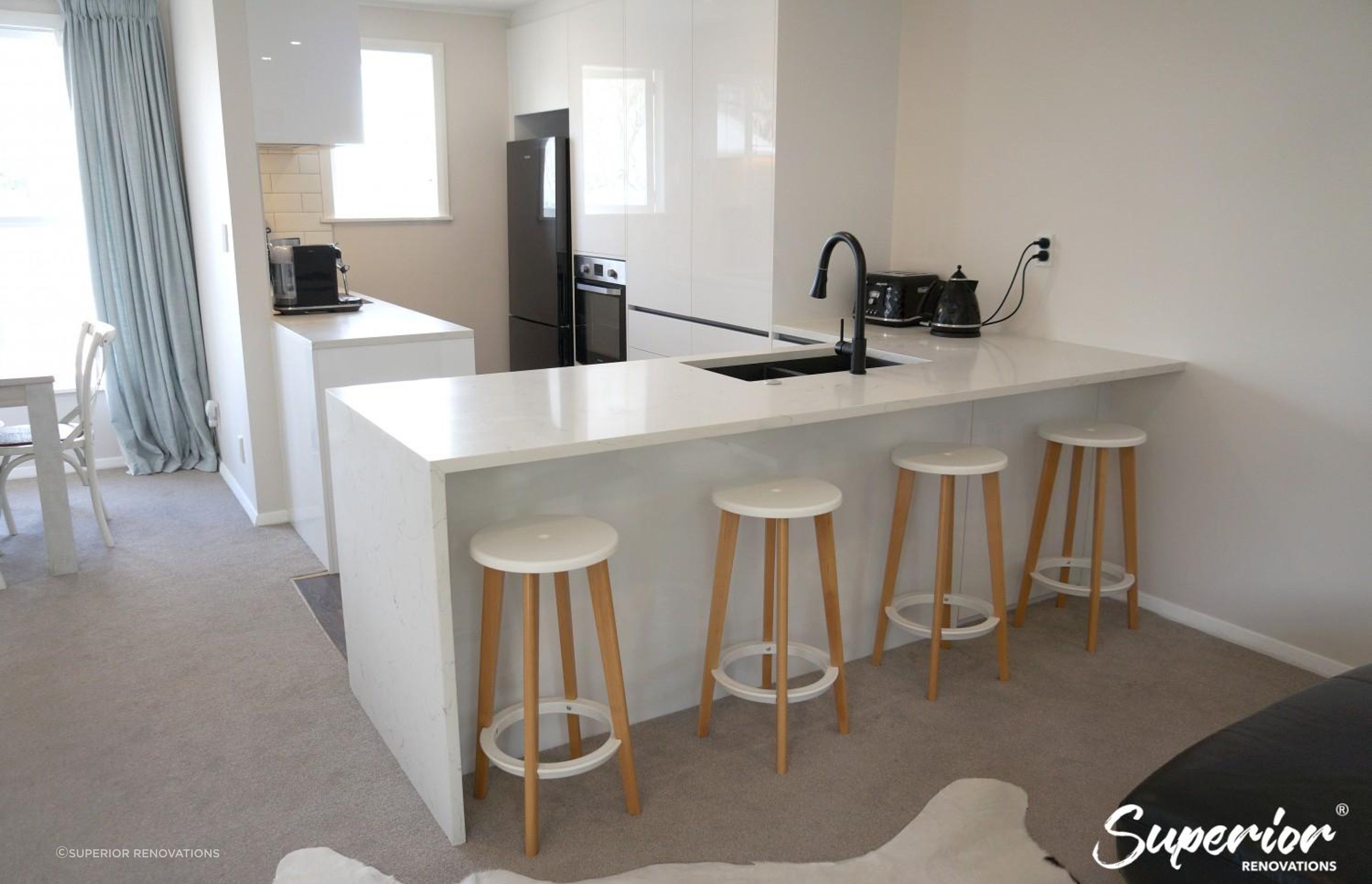 Kitchen renovation in Greenlane – The island doubles as a dining area, has a sink and counter space for prep and storage on the other side in form of cabinets