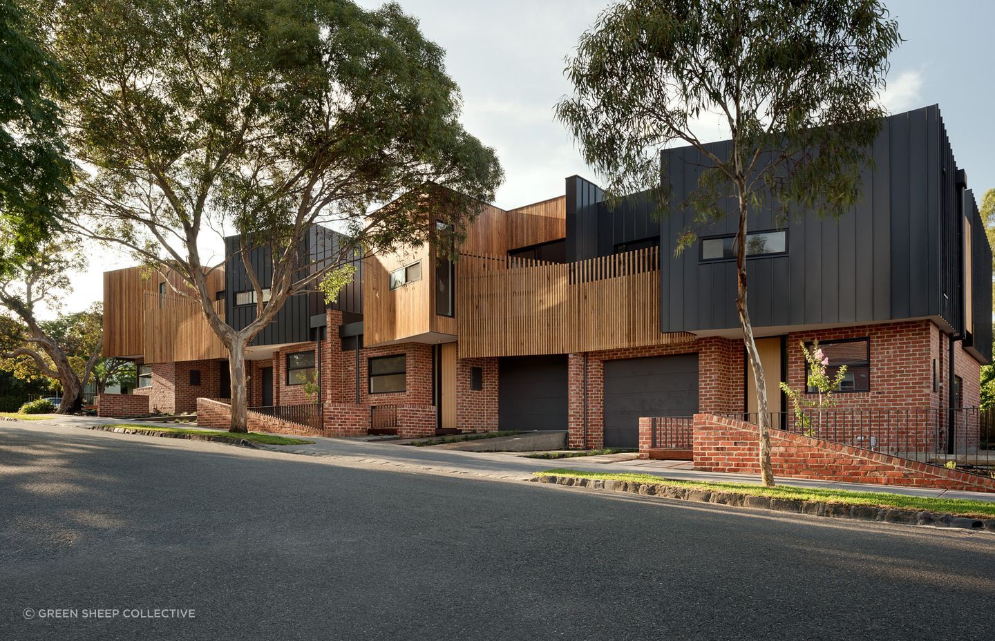 The exterior of these townhouses features a captivating blend of wood and brick. Photography by Emma Cross.