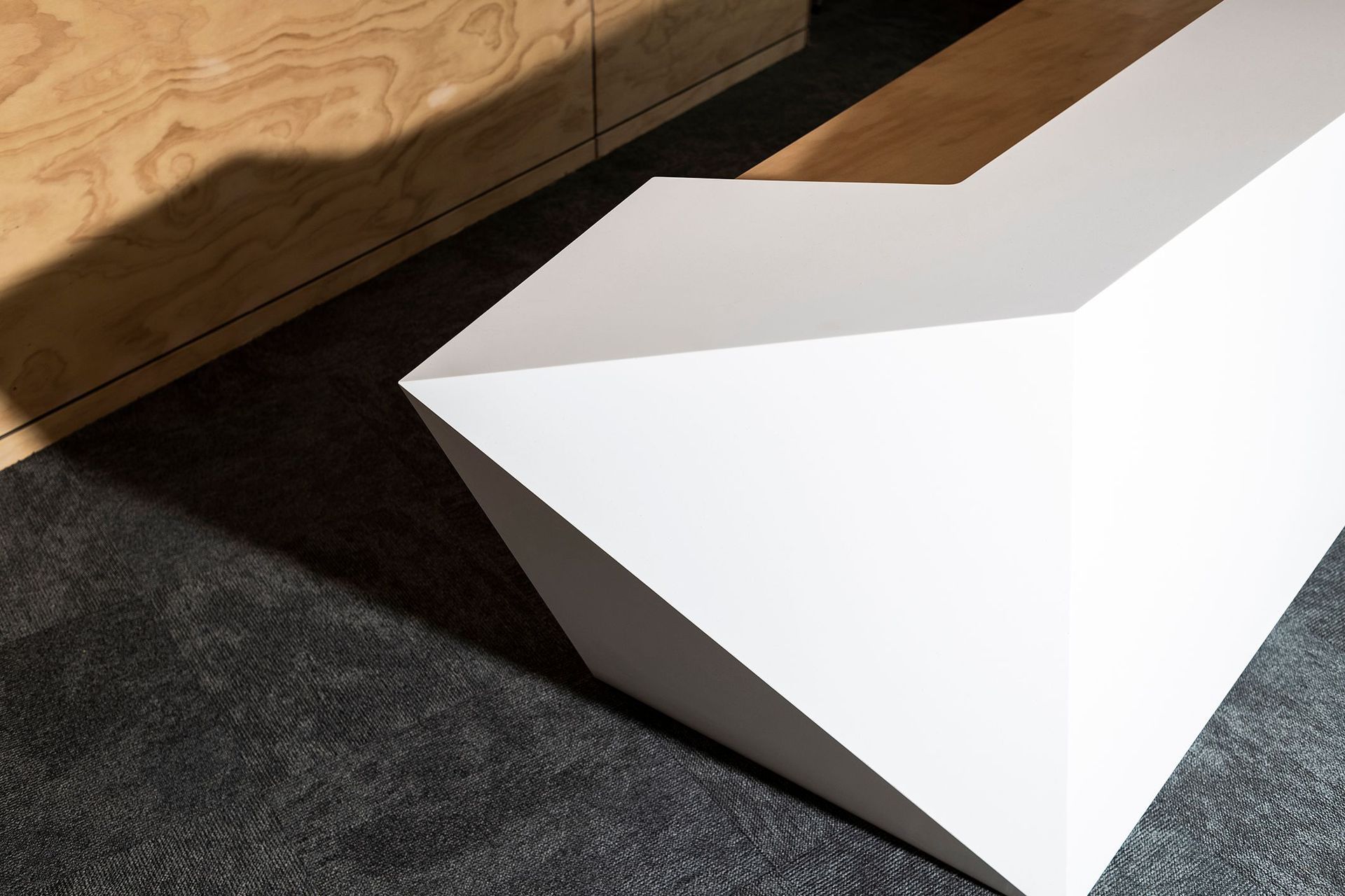 The striking geometric design of this reception counter was achieved by compound cutting nine sheets of Tavolo solid surface panels into the various component shapes, which were then seamlessly assembled into the finished product.