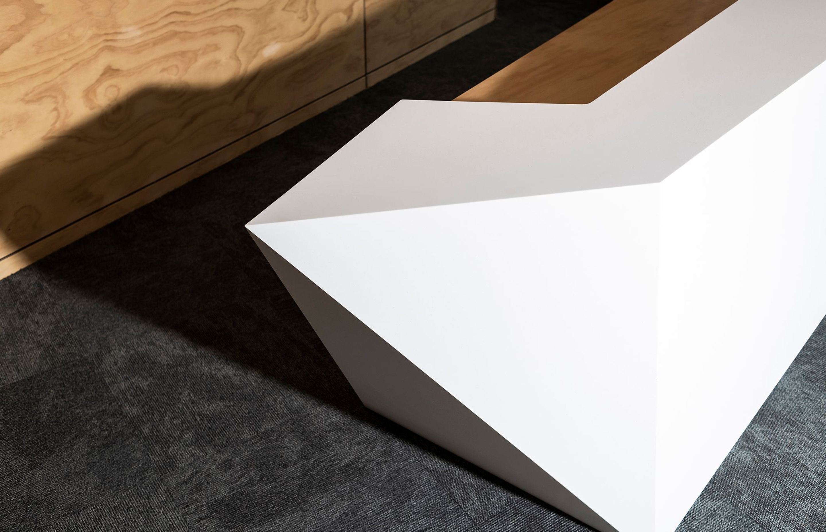 The striking geometric design of this reception counter was achieved by compound cutting nine sheets of Tavolo solid surface panels into the various component shapes, which were then seamlessly assembled into the finished product.