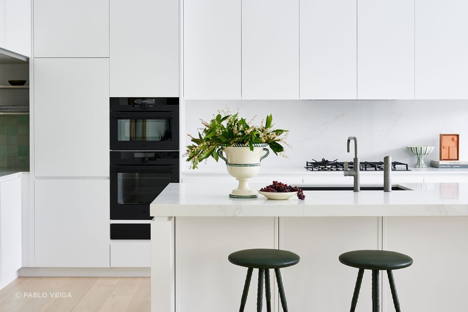 The kitchen and dining areas reflect the same refined minimalism seen throughout the home — warm timber, white joinery, and subtle textures.