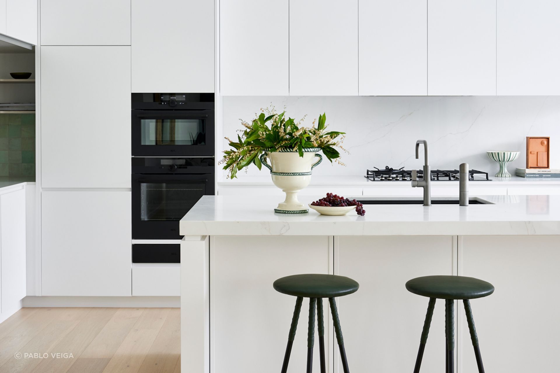 The kitchen and dining areas reflect the same refined minimalism seen throughout the home — warm timber, white joinery, and subtle textures.