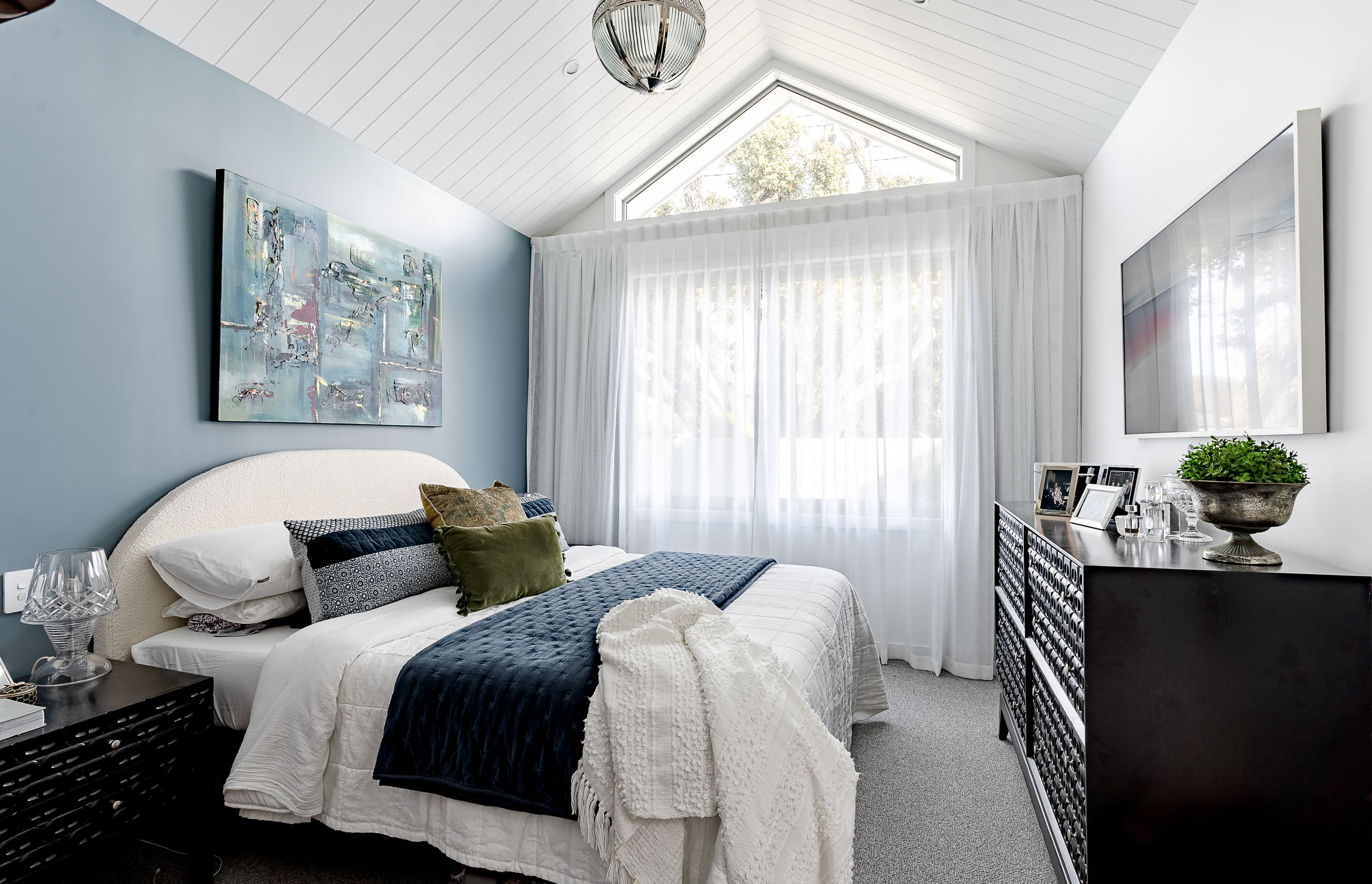 The smaller gable-roofed wing houses a bedroom, with the floor to ceiling window allowing for an abundance of natural light.