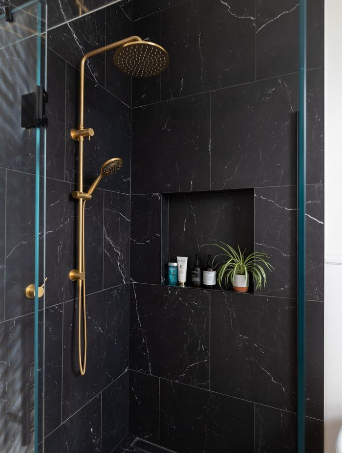 Brass tapware contrasts with the black tiles and complements the home's heritage features.