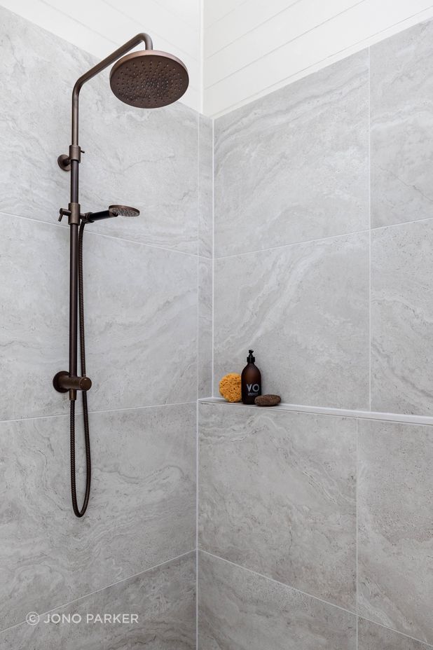 The Plumbline Shower Buddy Column in 'Aged Brass' contrasts with the textural tiles from Quantum.