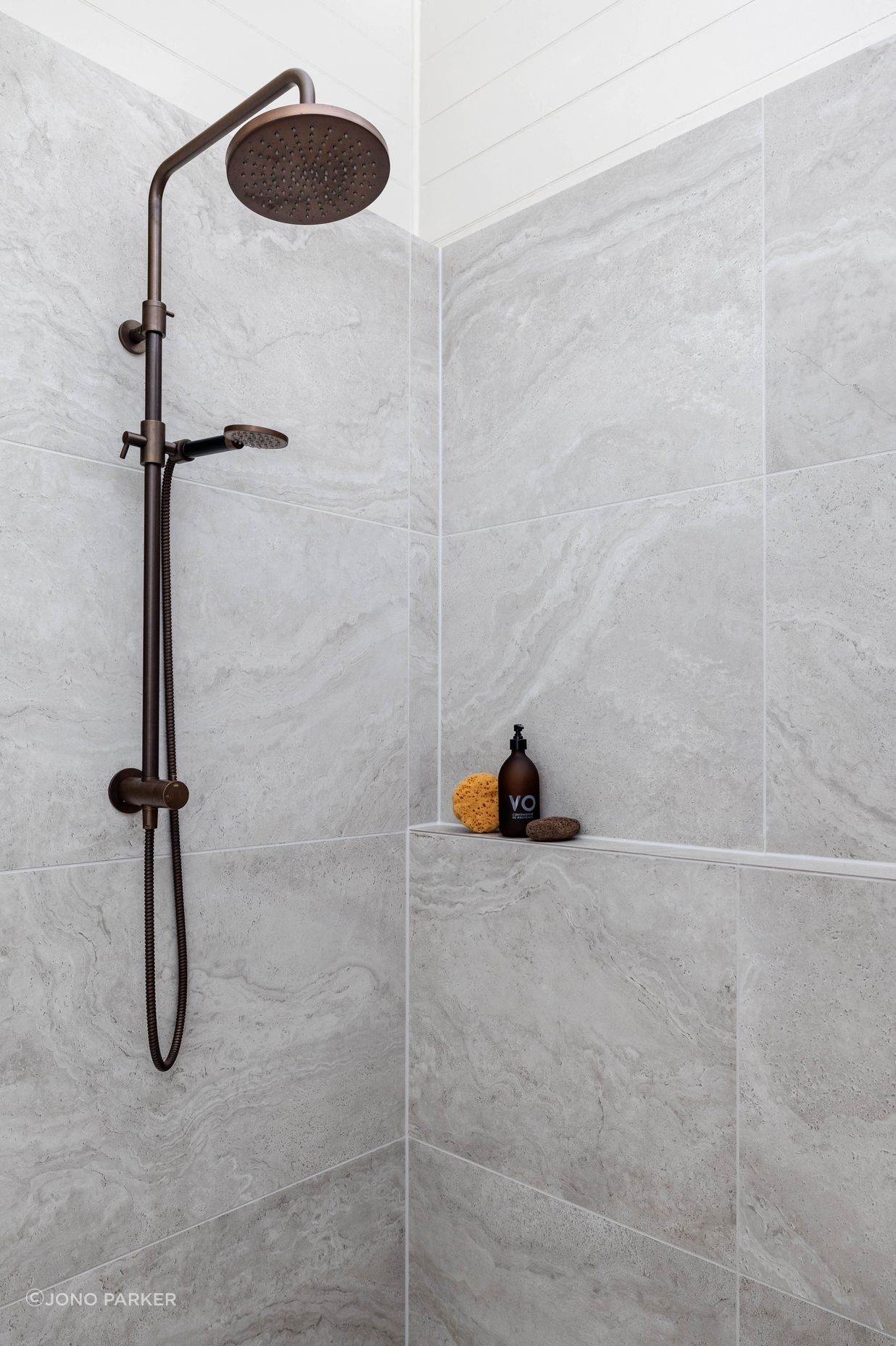 The Plumbline Shower Buddy Column in 'Aged Brass' contrasts with the textural tiles from Quantum.