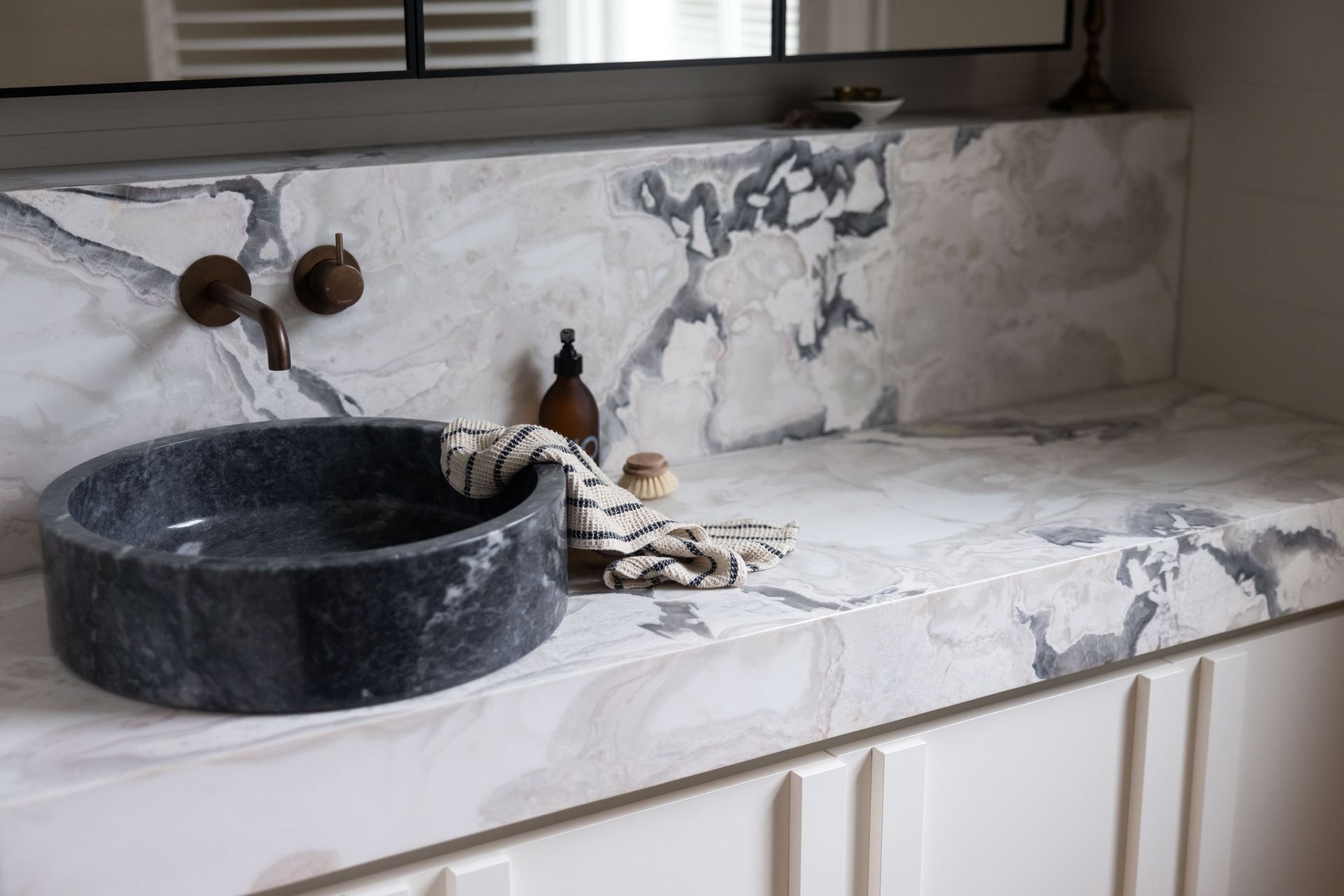 The Artedomus bluestone vessel basin contrasts with the lighter colours in the space, accentuating the marble's veining.