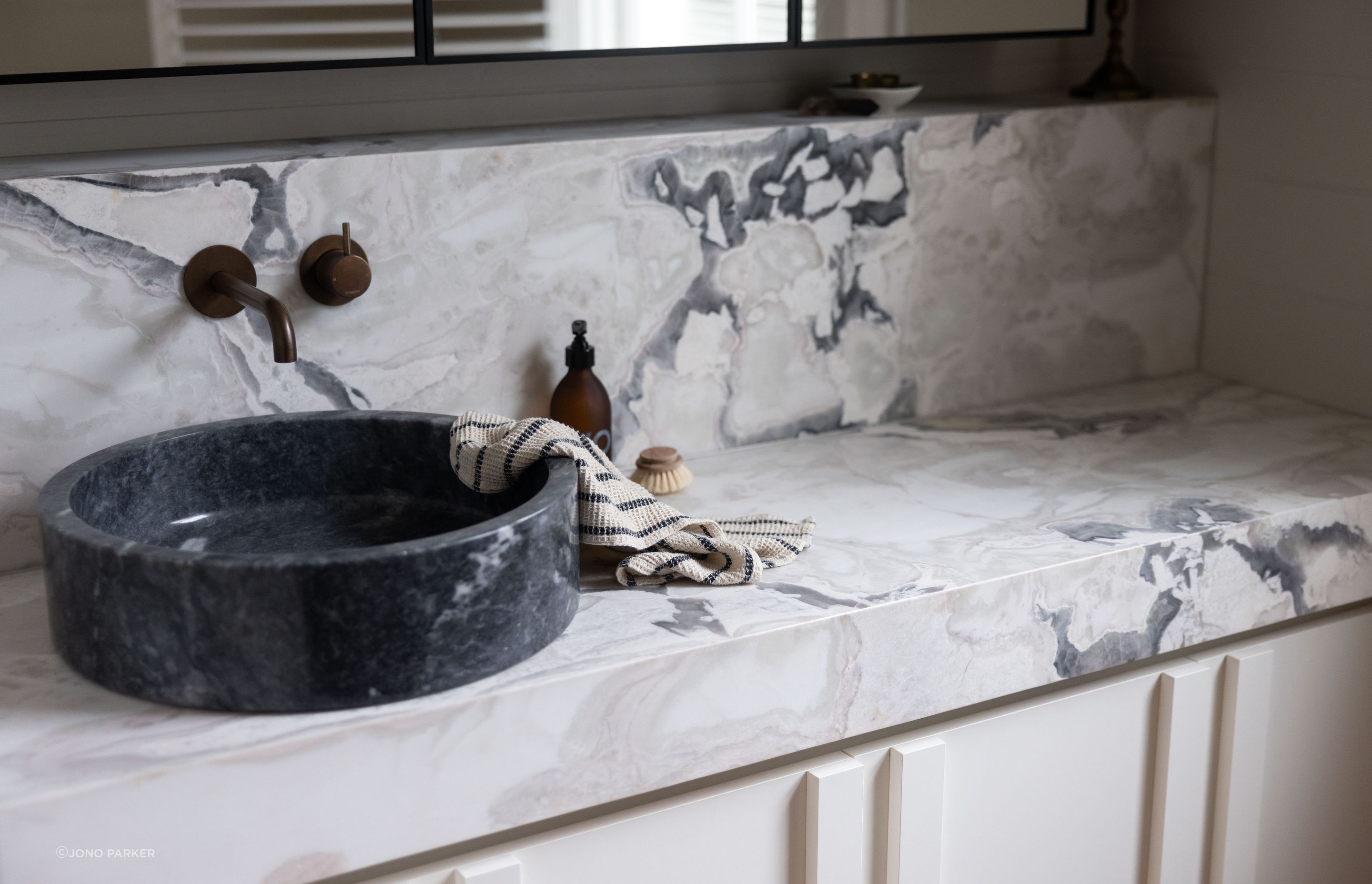 The Artedomus bluestone vessel basin contrasts with the lighter colours in the space, accentuating the marble's veining.