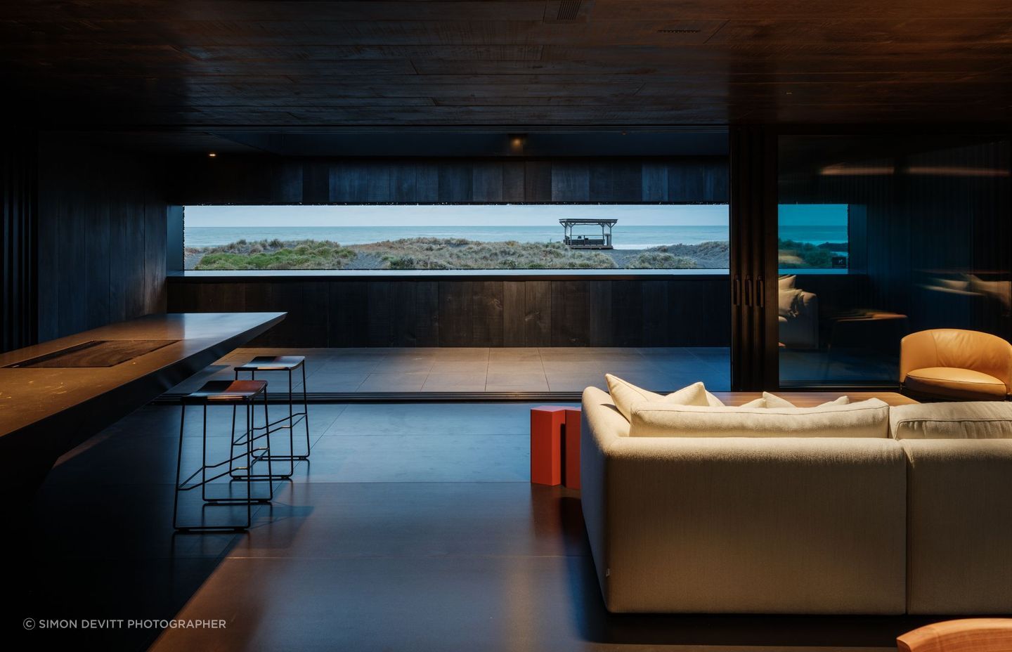 An inner reflection of the iconic black sands before it at The Bunker House in Piha, featuring VidaSpace's Consul Hand Grade Timber Flooring. | Photography: Simon Devitt Photographer