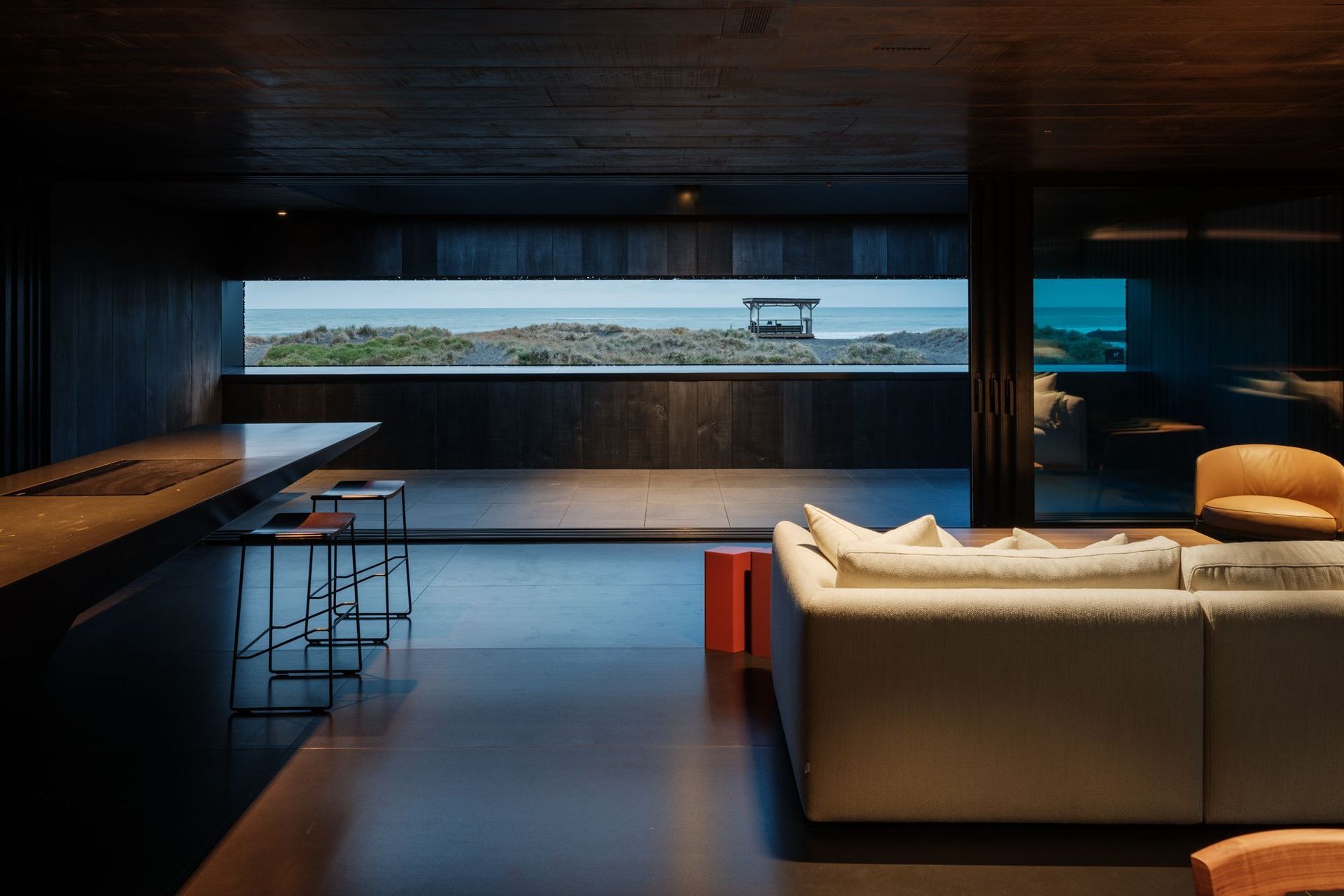 An inner reflection of the iconic black sands before it at The Bunker House in Piha, featuring VidaSpace's Consul Hand Grade Timber Flooring. | Photography: Simon Devitt Photographer