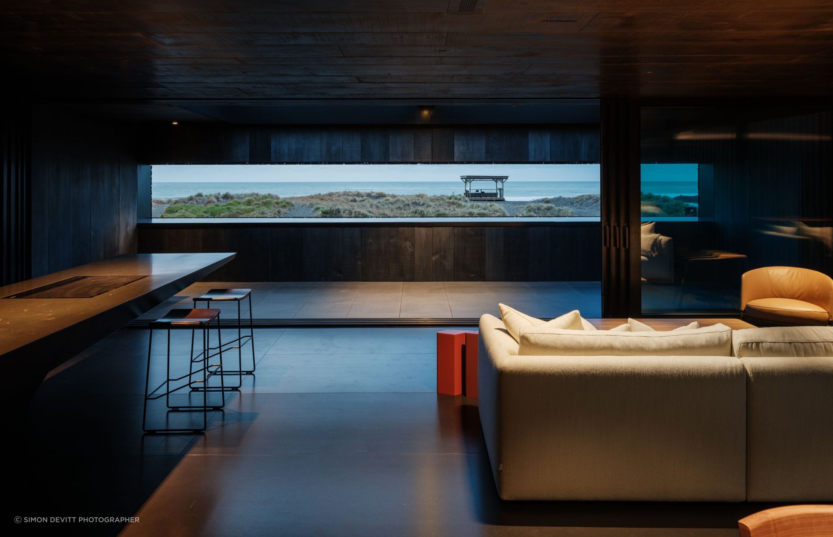 An inner reflection of the iconic black sands before it at The Bunker House in Piha, featuring VidaSpace's Consul Hand Grade Timber Flooring. | Photography: Simon Devitt Photographer
