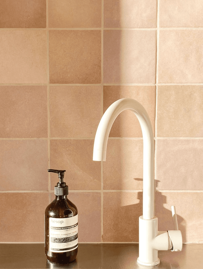 An ABI Interiors kitchen sink mixer in Almond pairs with the terracotta pink kitchen splashback.