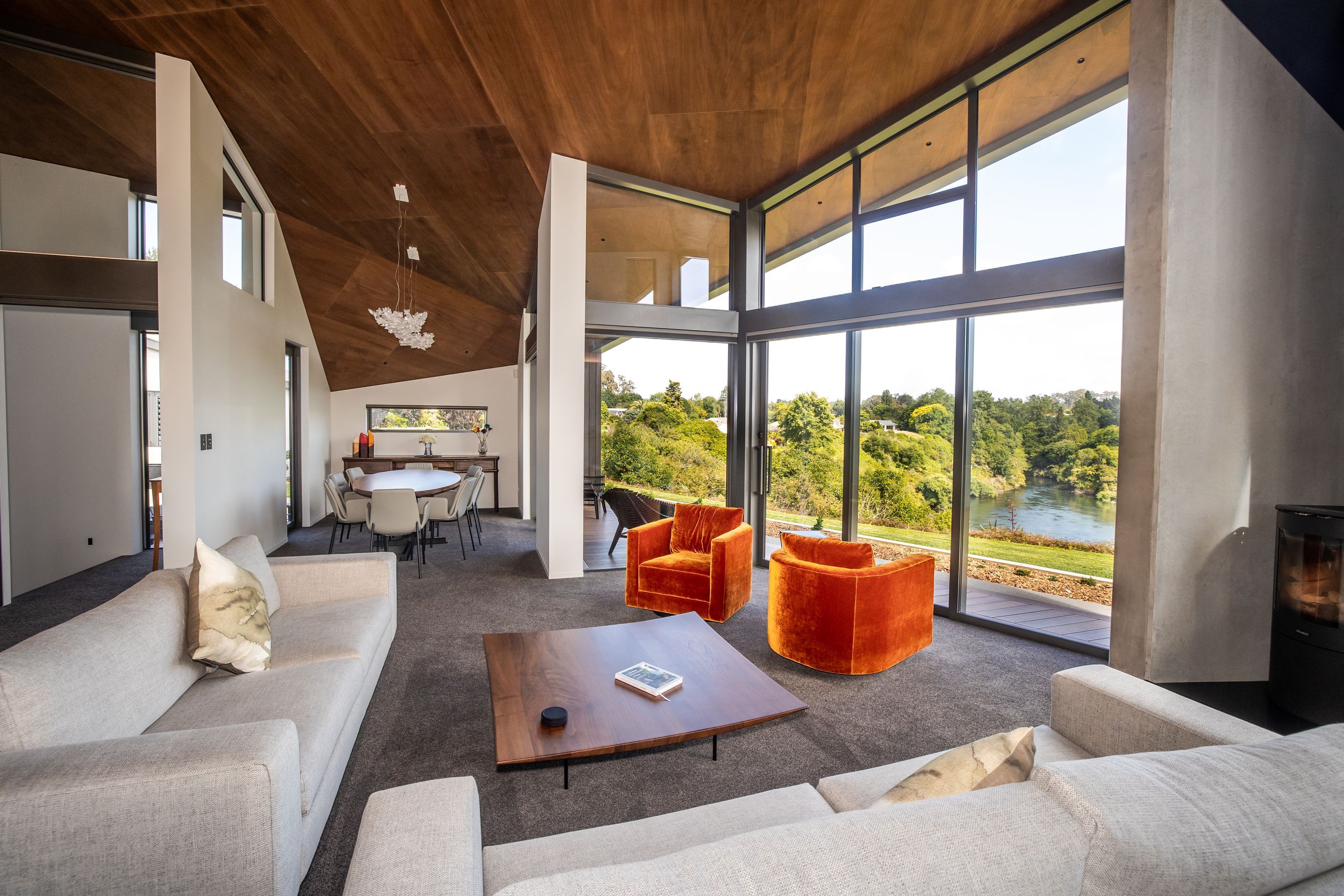 The lounge takes in stunning views of the river, while the timber lined ceiling angles down into a dining space.