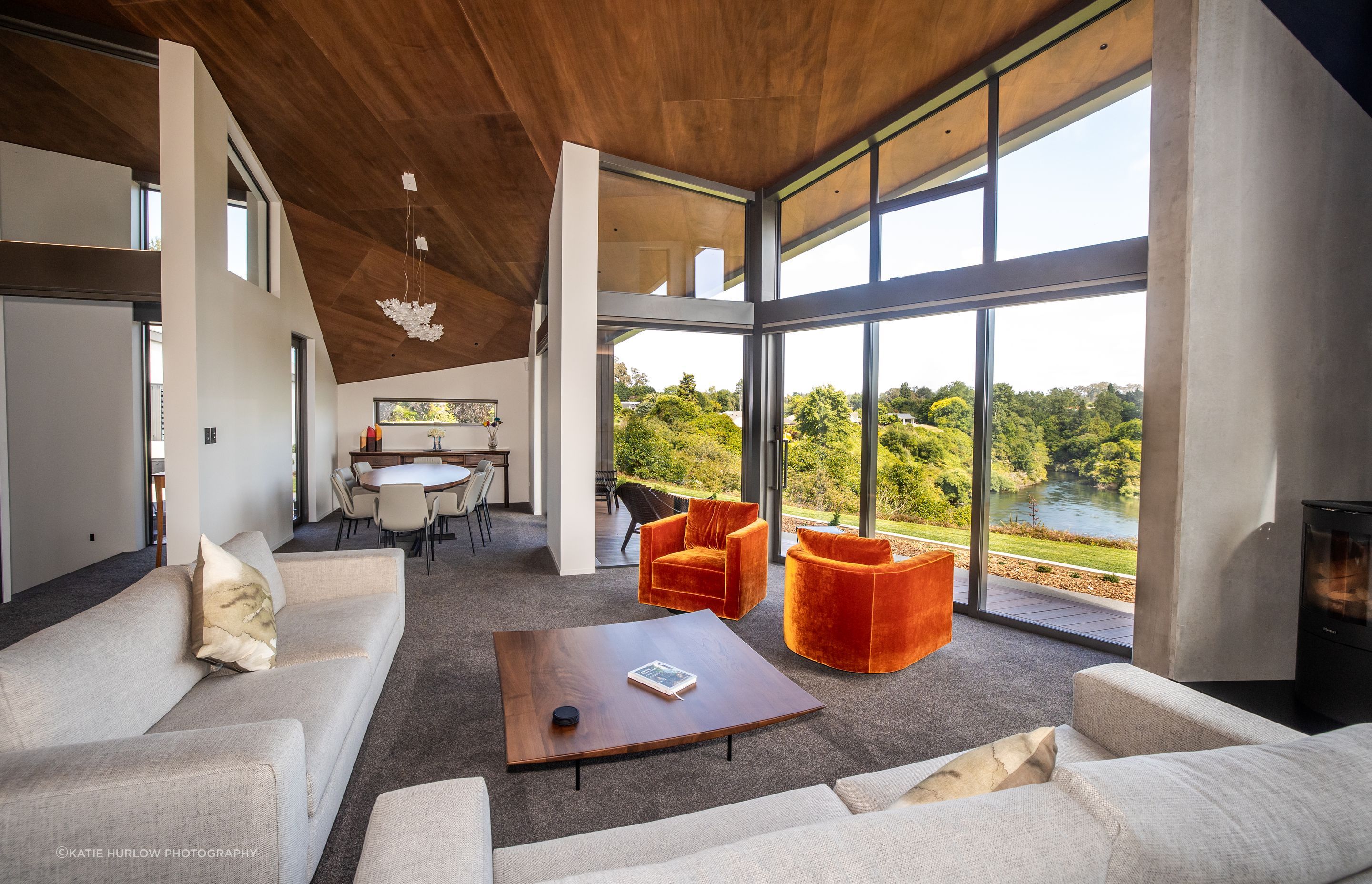 The lounge takes in stunning views of the river, while the timber lined ceiling angles down into a dining space.