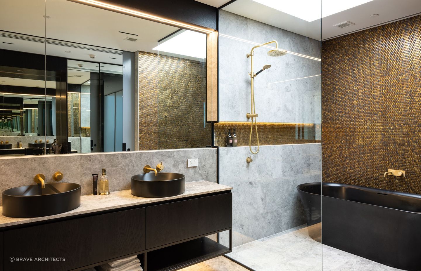 A luxurious bathroom impresses with a black freestanding bathtub, brass fittings and a copper penny round feature wall.