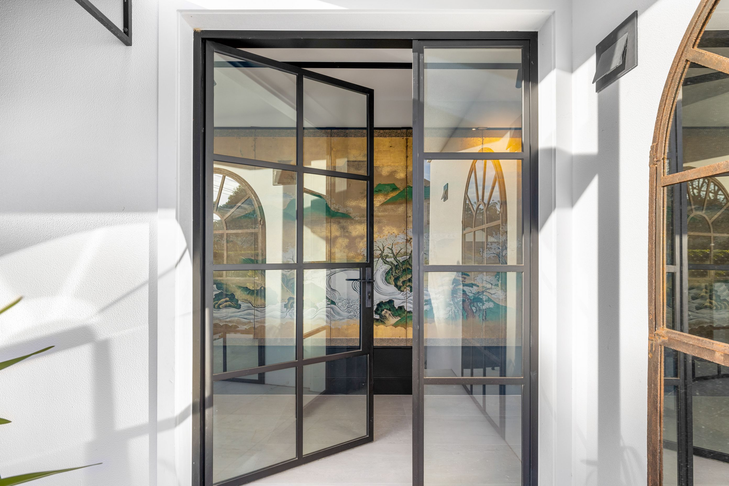 To enhance the entry to the home, an antique Japanese screen lies behind the steel entrance doors, drawing visitors in.