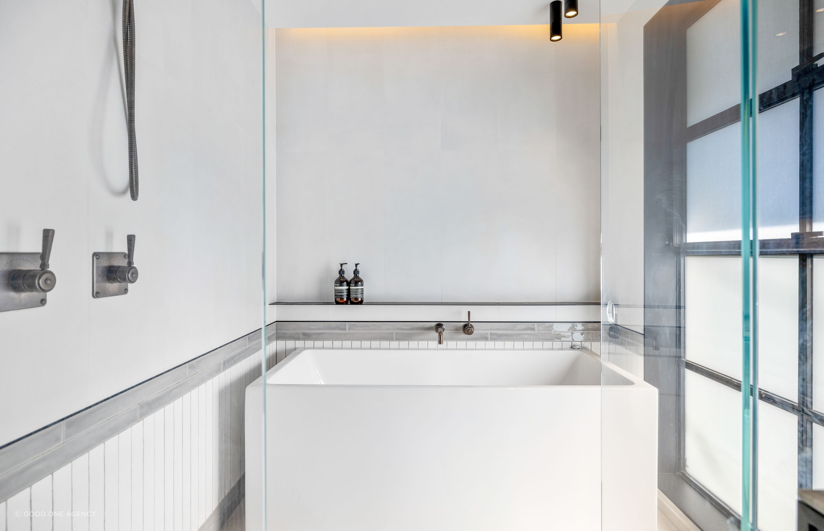 A family bathroom features handmade tiles soldiered around the base of the walls and a Japanese-style bath.