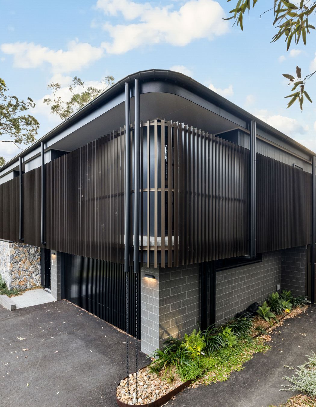 The form of the home avoids sharp lines, with the bronze coloured aluminium battens creating a soft, perforated.
