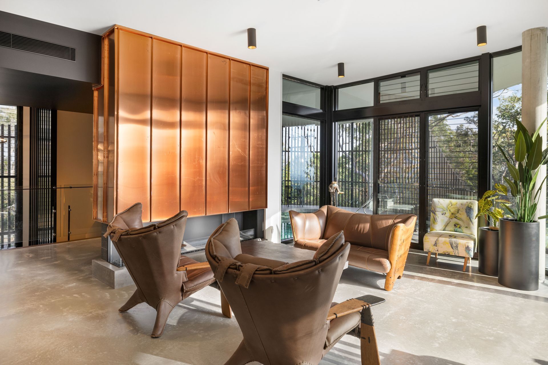 The double-height stairwell transitions directly into the main living space, which features a fireplace clad in copper.