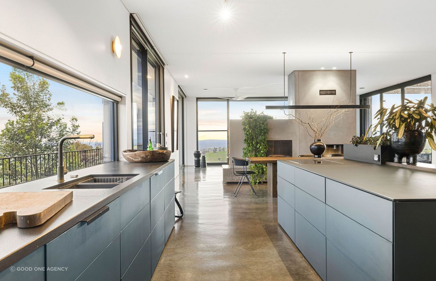 The home's petroleum-toned, glass kitchen creates warmth amid masses of floor-to-ceiling glass
